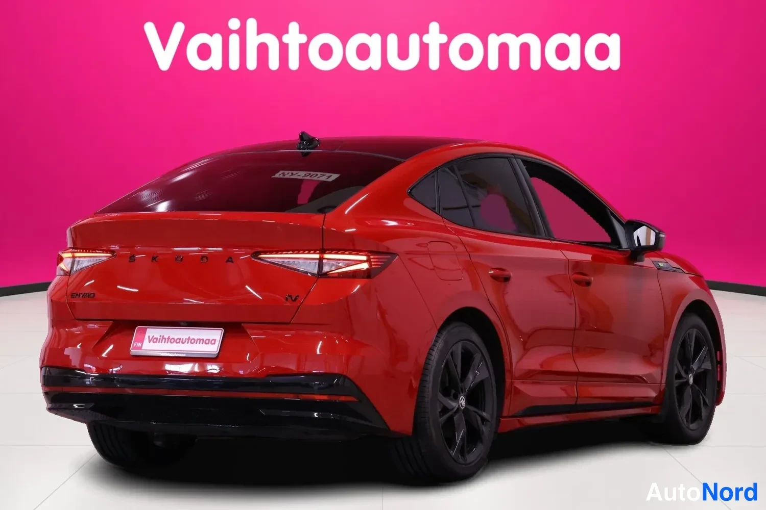 Takaviisto: Punainen henkilöauto takaosalta ja sivulta, takavalot ja vaihtoautomaan rekisterikilpi näkyvät.