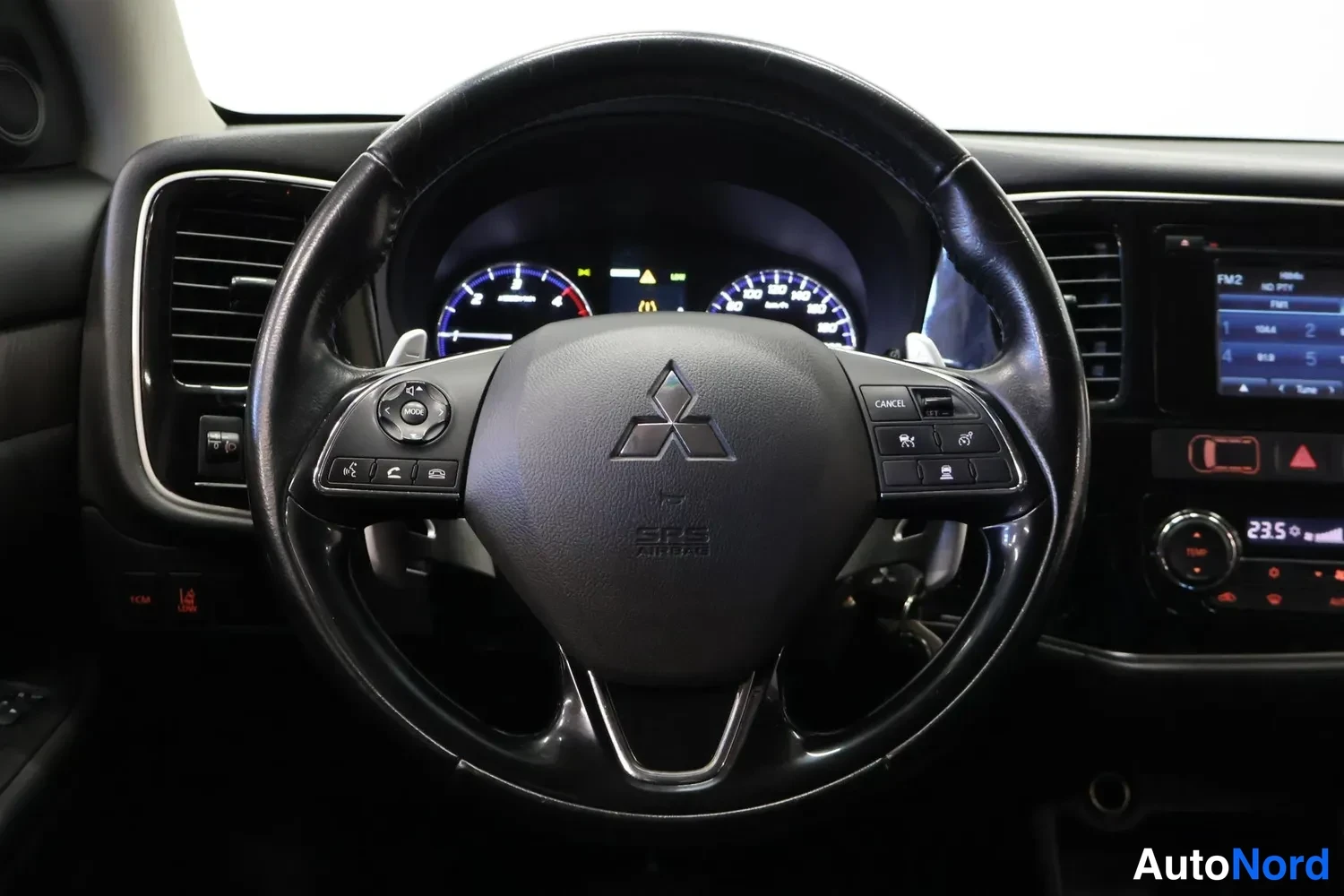 Muu: Ohjauspyörä suoraan edestä kuvattuna, Mitsubishi-logo ja SRS AIRBAG -merkintä keskussa, molemmin puolin monitoimipainikkeet, taustalla mittaristo ja infotainmen
