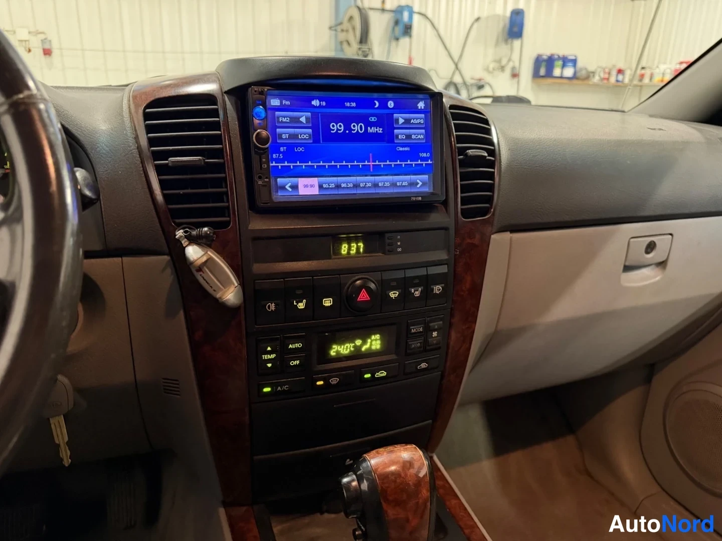 Muu: Keskikonsolin kuva: lisätyö yo. radio ja keskusloiset ja ilmastoinnin (AUTO, A/C) painikkeet, näytöllä 24,0°C ja radio 99,90 MHz.