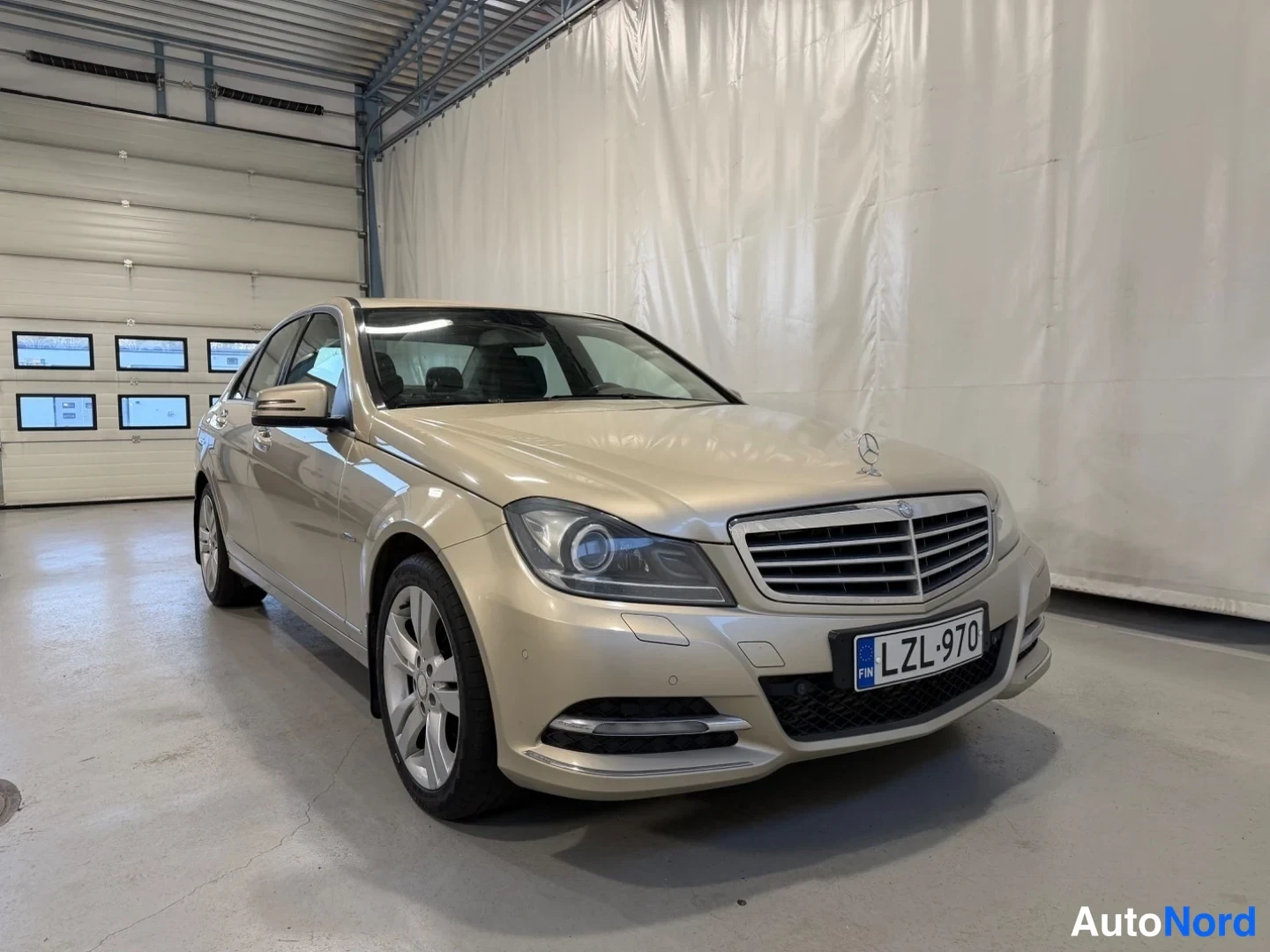 Etuviisto, nokka oikealle: Mercedes-Benz C-sedan etukenosta oikealta, beige väri, rekisteritunnus.