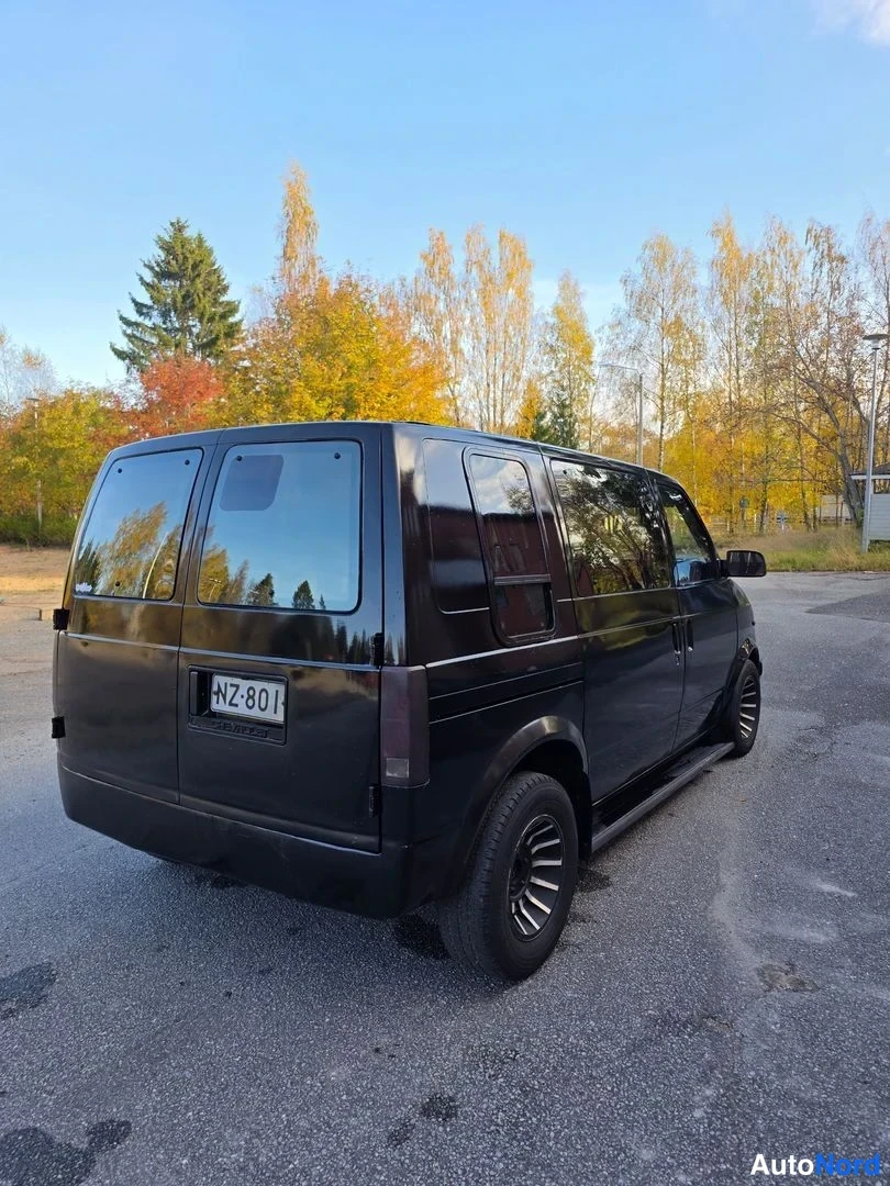 Takaviisto: Mustan Chevrolet Astro -pakettiauton takaosa ja sivu kuvattuna takaa, rekisterikilpi NZ-801, takaikkunat ja kattoteline näkyvät.