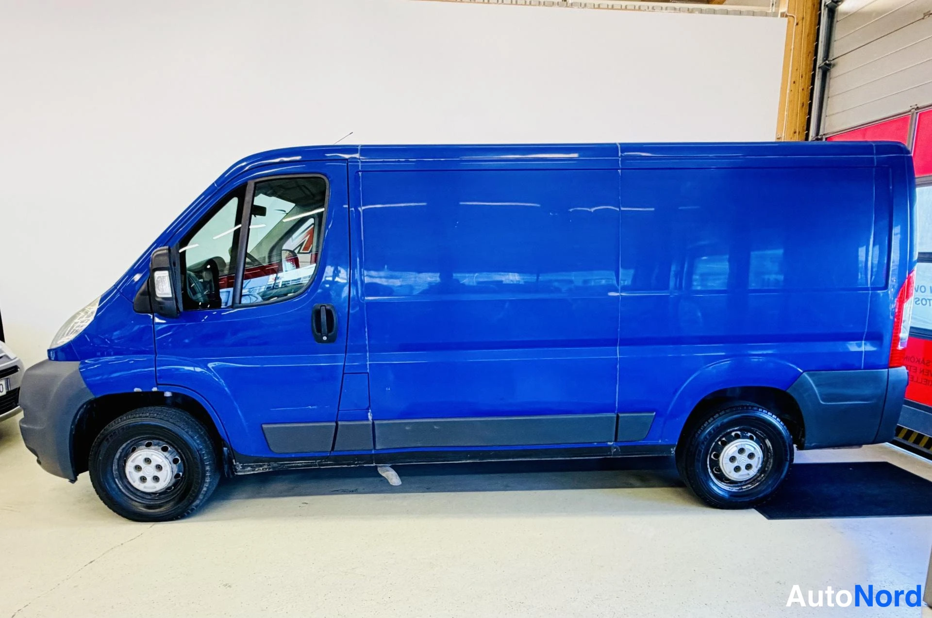Sivulta: Sininen Citroën Jumper -pakettiauto sivulta vasemmalta sisätiloissa.