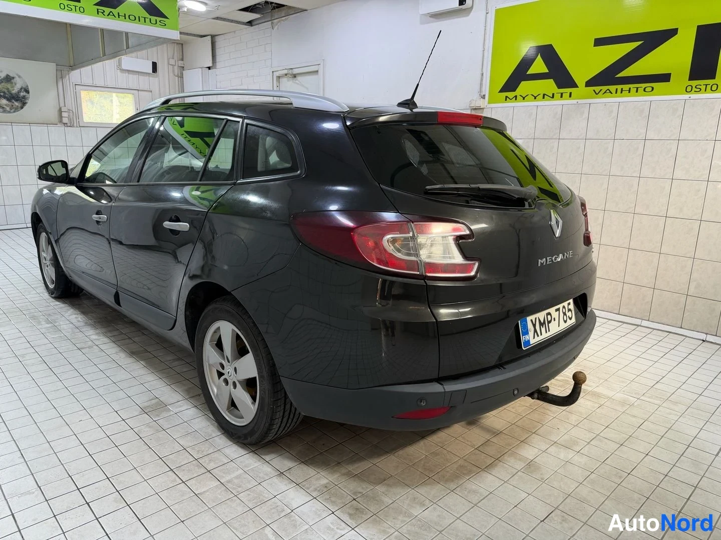 Takaviisto: Taka kolmasosakulma: musta Megane Sport Tourer, kattotelineet ja vedettävä koukku näkyvät.
