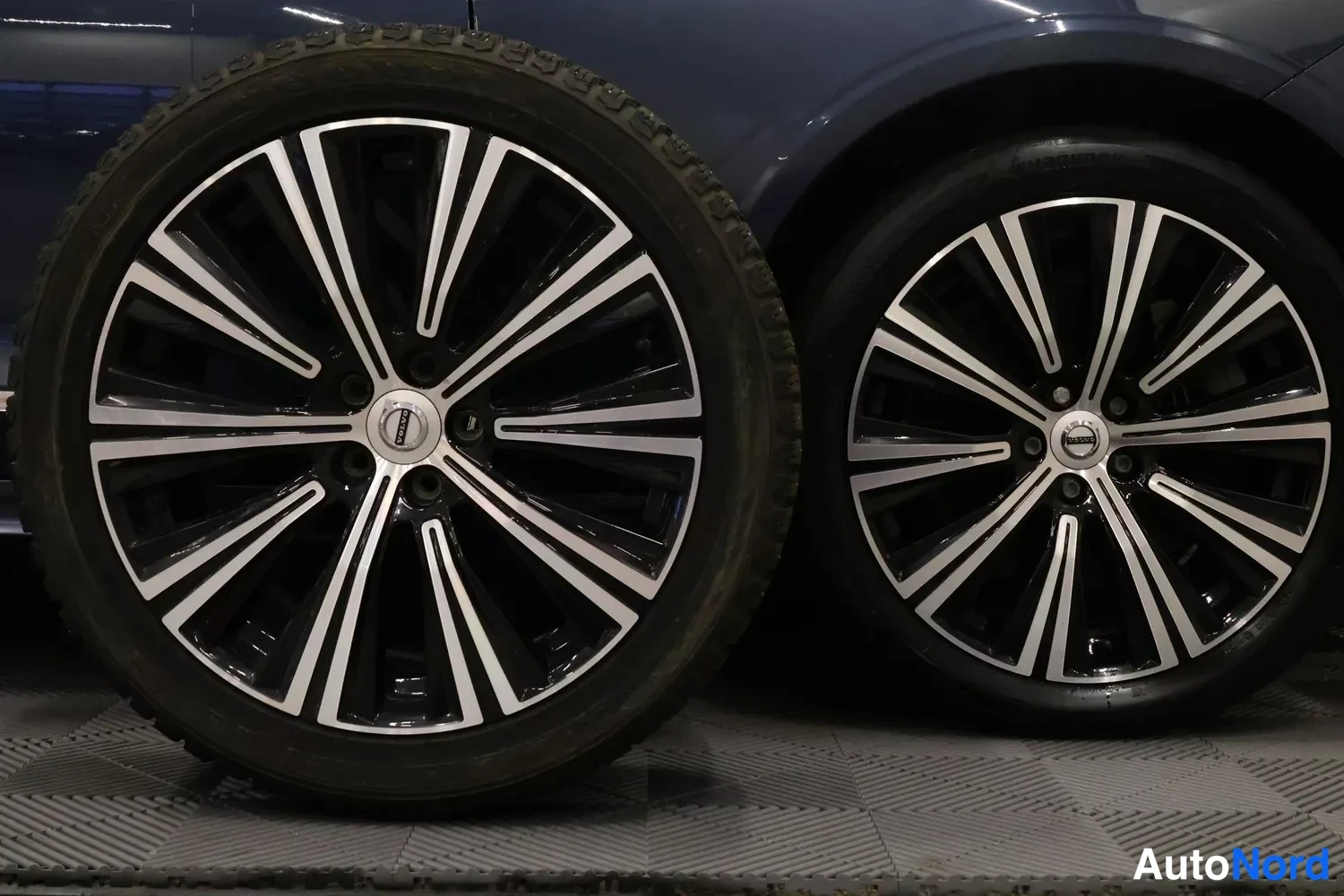 Yksityiskohta: Kaksi Volvo-teräsvellereunusta kumirenkineen kuvattuna lähikuvana sisätiloissa.