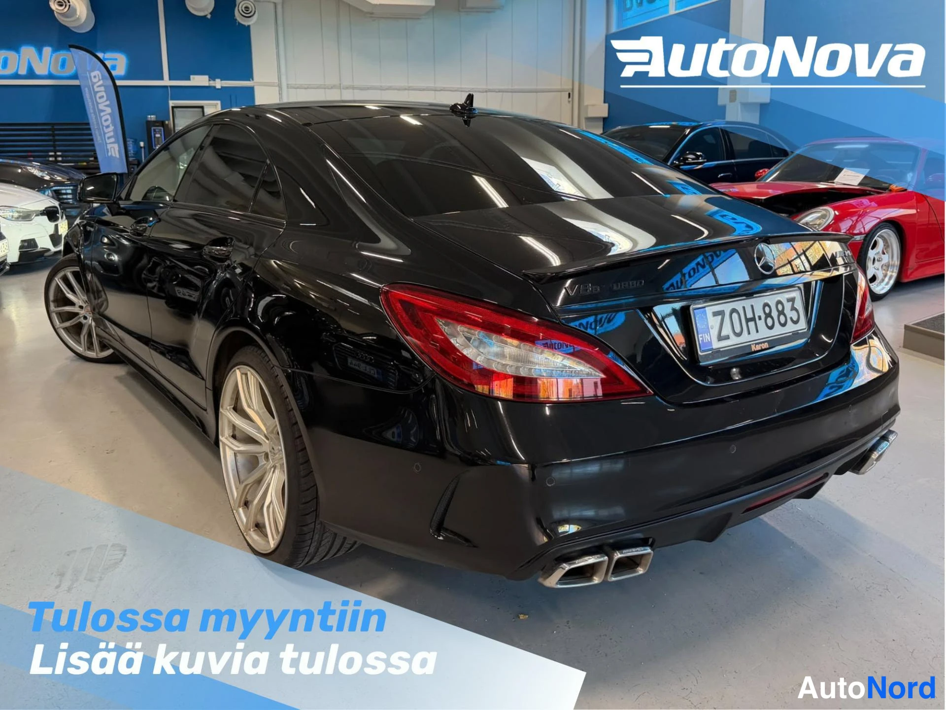 Takaviisto: Mustan Mercedes-Benzin takakulmanäkymä sisätiloissa, takavalot, neljä pakoputkea ja rekisterikilpi näkyvät.