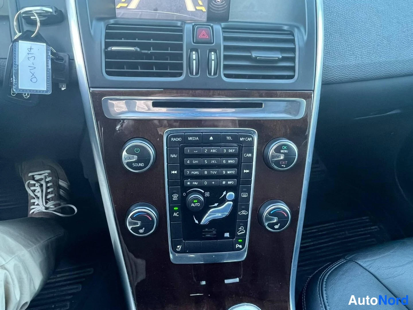 Muu: Keskikonsolin näyttö: radio- ja ilmastointiohjaimet, painikkeet RADIO, MEDIA, TEL, MY CAR, NAV, CAM, AUTO ja AC; kojetaulun näytön yläosassa parkkitilanne.