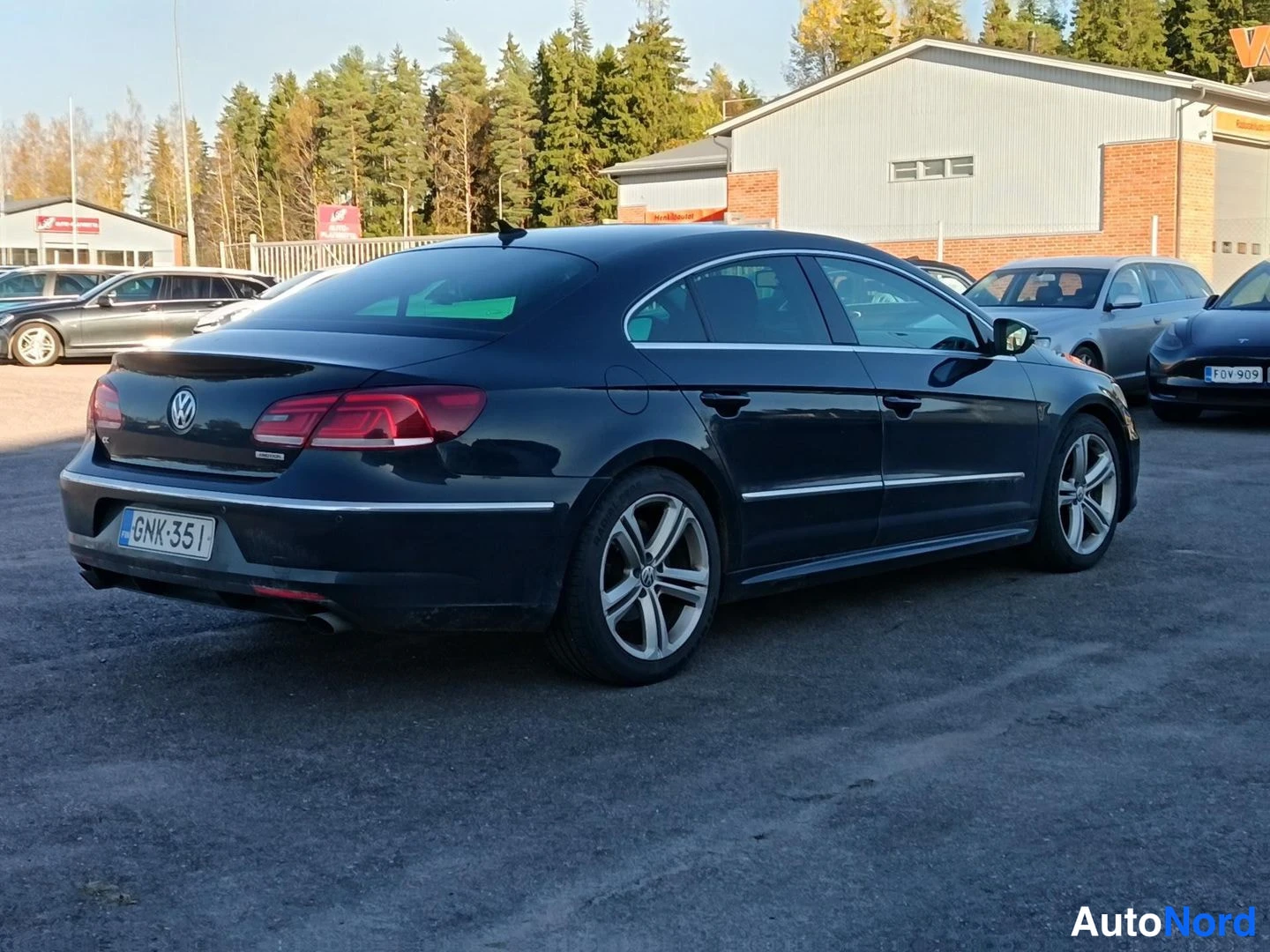 Takaviisto: Mustan Volkswagen CC:n takaosa ja vasen kylki parkkipaikalla, takavalot ja rekisterikilpi näkyvät.