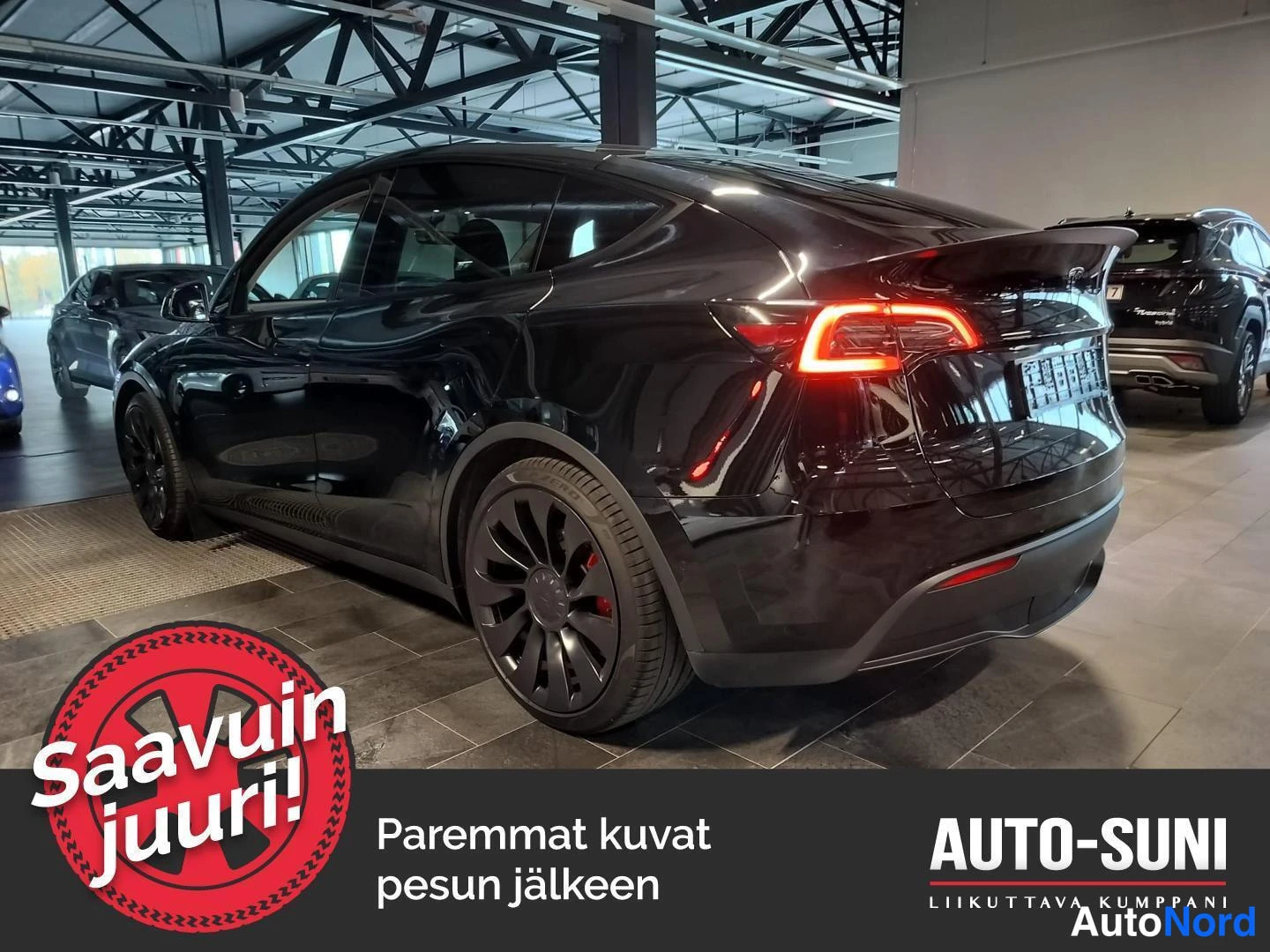 Takaviisto: Musta Tesla Model Y takakulmasta oikealta, takavalo syttyneenä, autonhallissa.