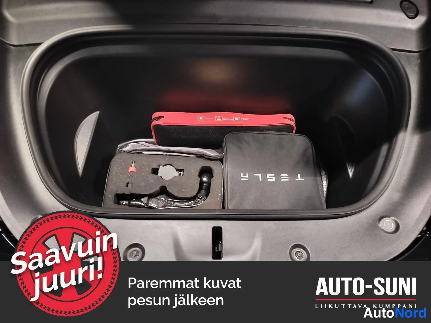 Muu: Tavaratilan alakolo, jossa näkyy punainen ja musta varustelaukku sekä Tesla-merkkinen suojapussi