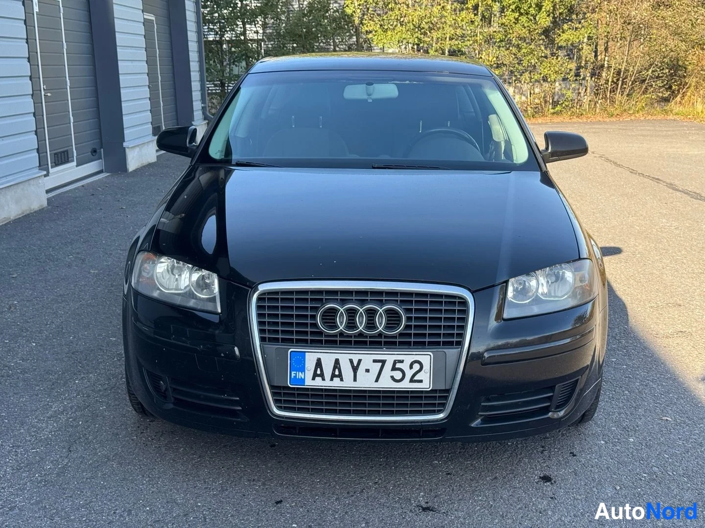 Edestä: Musta Audi edestä päin kuvattuna, etugrilli ja rekisteritunnus.