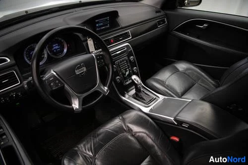 Muu: Volvo V70:n etuistuimet ja keskikonsoli kuljettajan puolelta kuvattuna; nahkaiset istuimet, automaattivaihteen valitsin ja kojelaudan näyttö näkyvät.