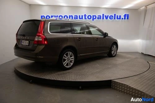 Takaviisto: Auton takaosa ja vasen sivu kolmeneljänneskuvassa, ruskea farmariauto hallissa alustalla.