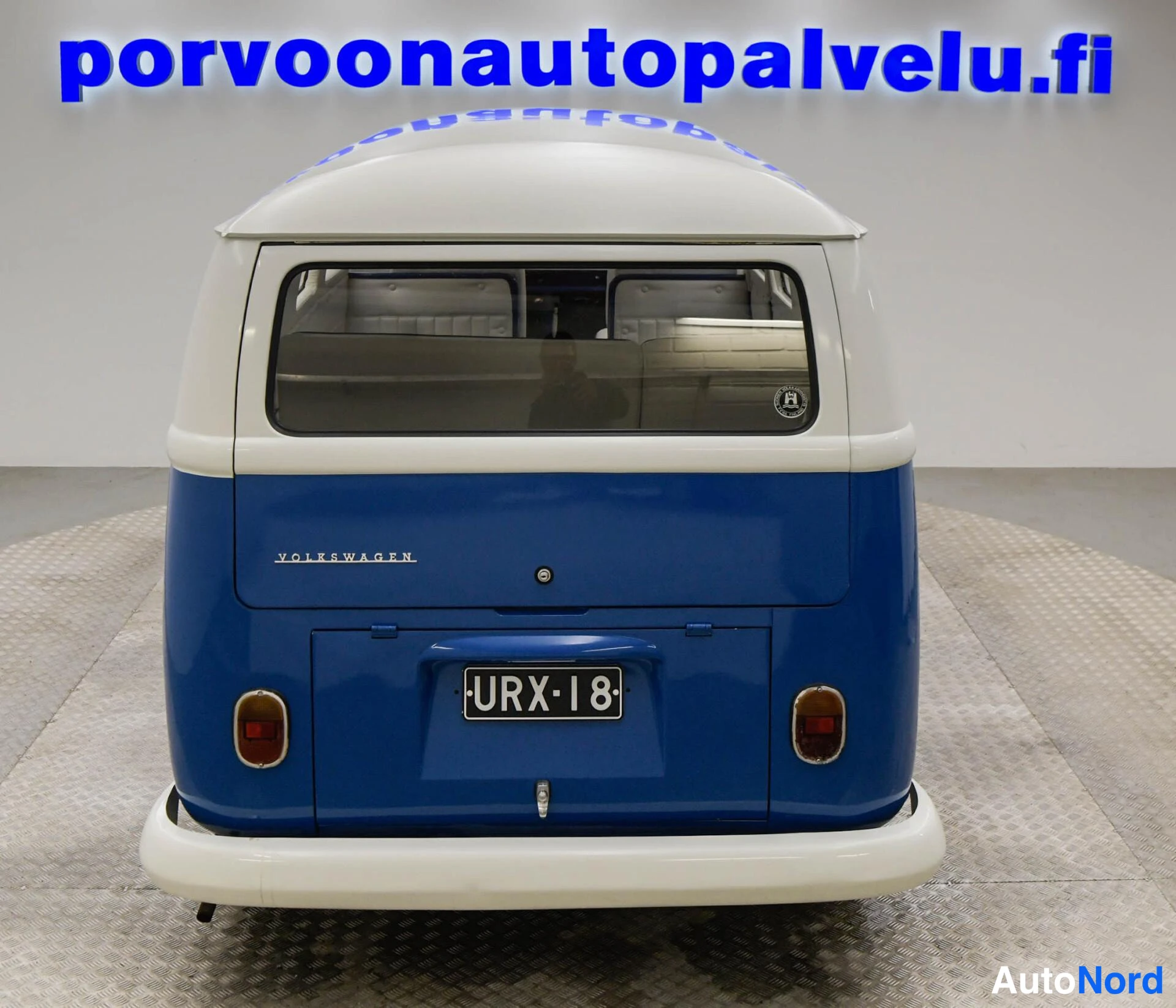 Takaa: Sinivalkoisen Volkswagen -pakettiauton takaosan suora kuvakulma, rekisterikilpi.