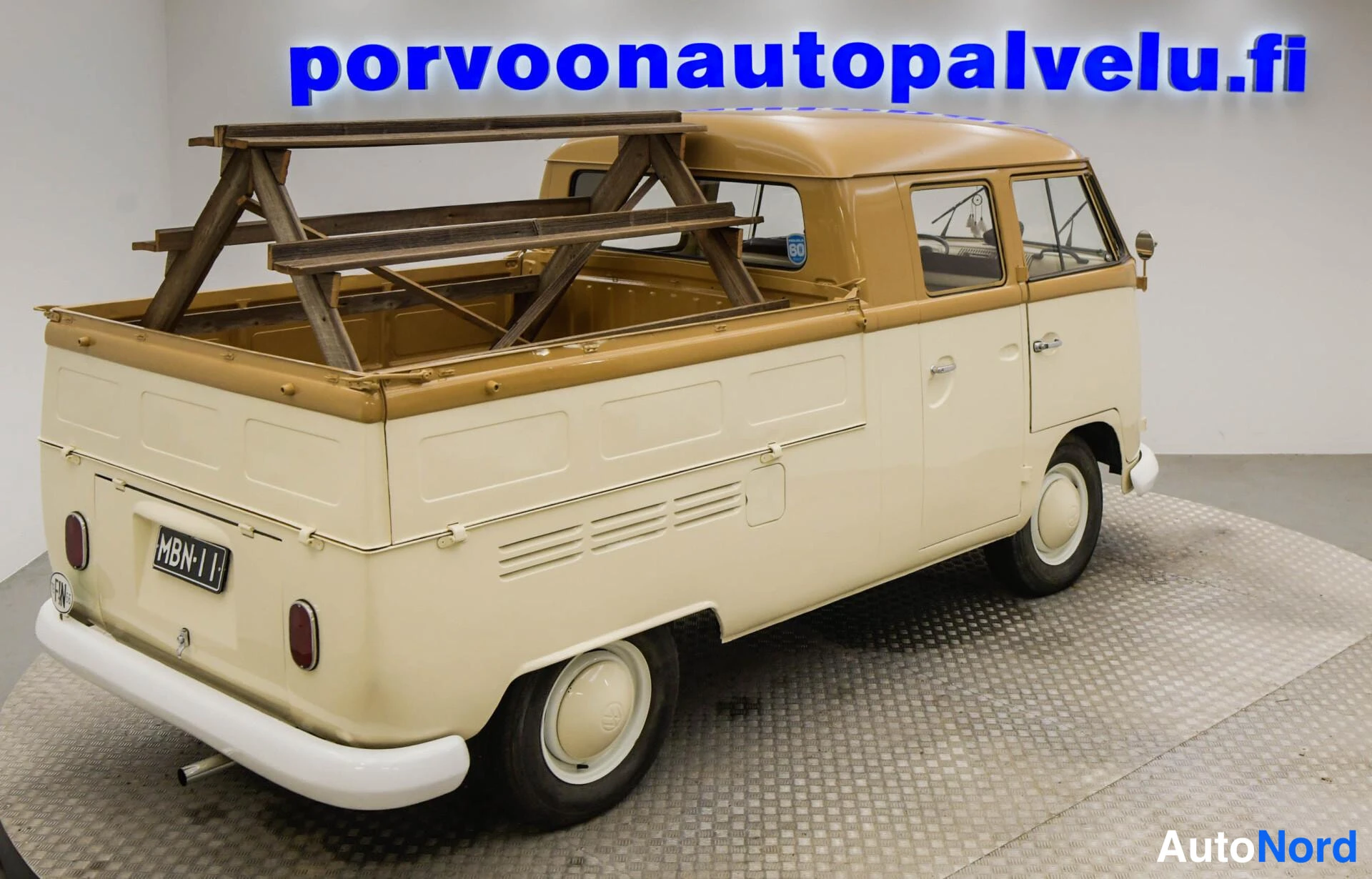Takaviisto: Kaksivärinen Volkswagenin lava-auto tak kolmasosan kuva oikealta; avolava puutelineellä, sivuovet ja -rekisterikilpi näkyvät.