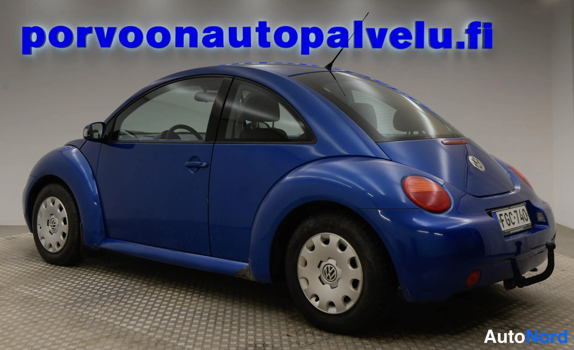 Takaviisto: Sininen Volkswagen New Beetle takakulmakuva, rekisterikilpi.