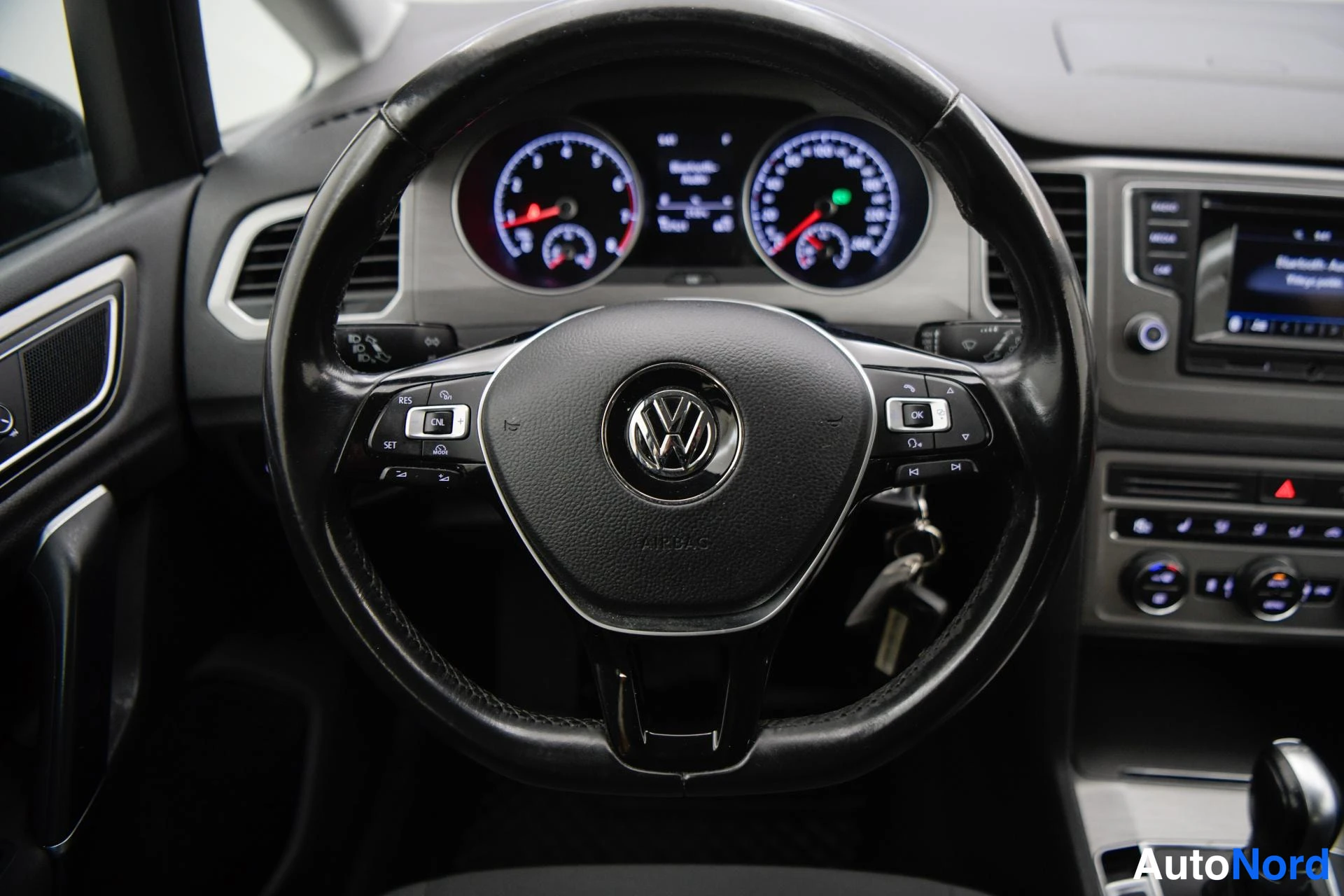 Sivulta: Ohjaamosta: VOLKswagen-merkkinen monitoimiohjauspyörä, kombo, infotainmentnäyttö ja automaattivaihteiston valitsin.