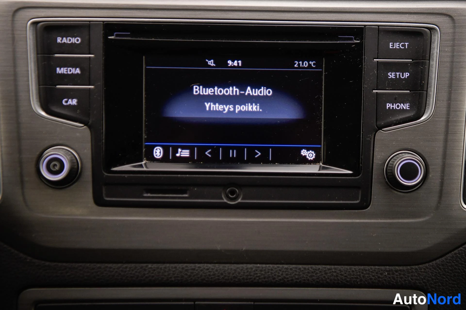 Yksityiskohta: Auton kojelaudan radioyksikkö, jonka näytössä lukee 'Bluetooth-Audio' ja 'Yhteys poikki.', kello 9:41 ja 21,0 °C; painikkeet RADIO, MEDIA, CAR, EJECT, SETUP ja