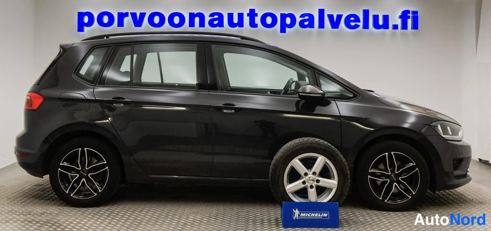 Etuviisto, nokka oikealle: Sivukulmakuvassa tummanharmaa Volkswagen Golf Sportsvan; kylki ja etukulma näkyvät, ylimääräinen konepellin varrella seisova tamppa osuu etupyörän kohdal