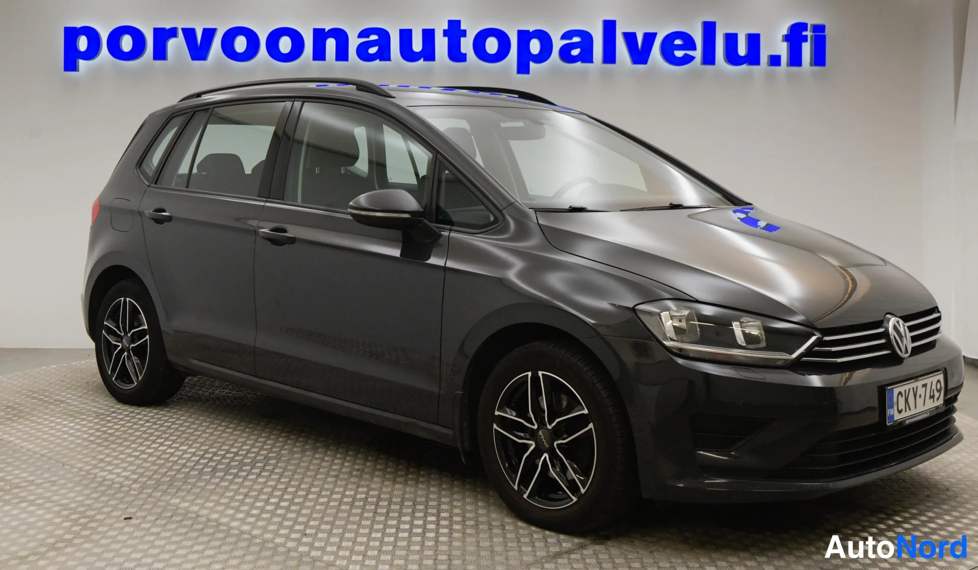 Etuviisto, nokka oikealle: Volkswagen Golf Sportsvan kolmella neljäsosakulmalla, kylki ja keula näkyvät; tummanharmaa korimaali, rekisteritunnus, kattokaiteet ja mustat monipuolise
