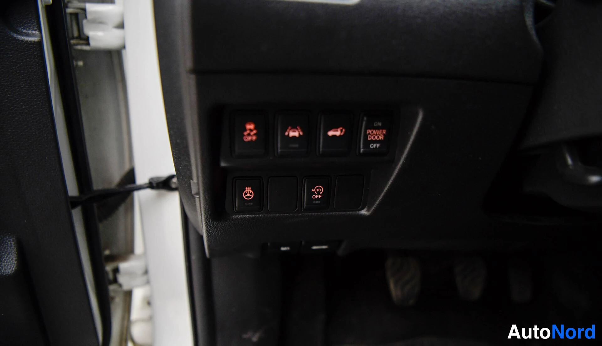 Yksityiskohta: Rattipylvään kytkinpainikkeet: kamera OFF, Park & Ride -symboli, Power Door Off -kytkin, ESP OFF, rattilämmityksen OFF-kytkin ja AISIN Off -kytkin.