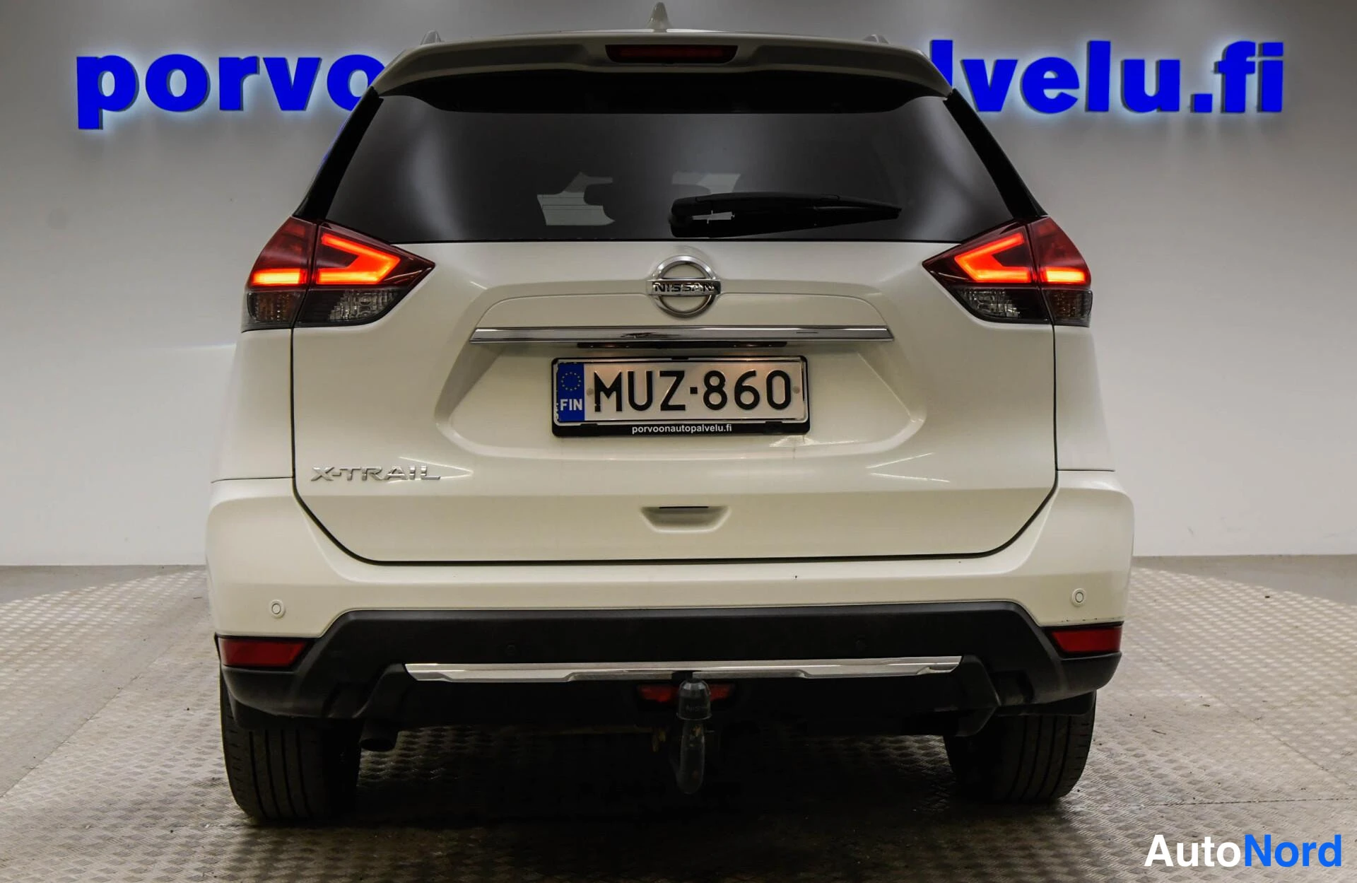 Takaa: Nissan X-Trail takaosan suora-näkymä, takavalojen pilkut syttyneinä, rekisteritunnus, X-Trail-merkintä ja tunnusb. Sukipesä ja tunnusb.