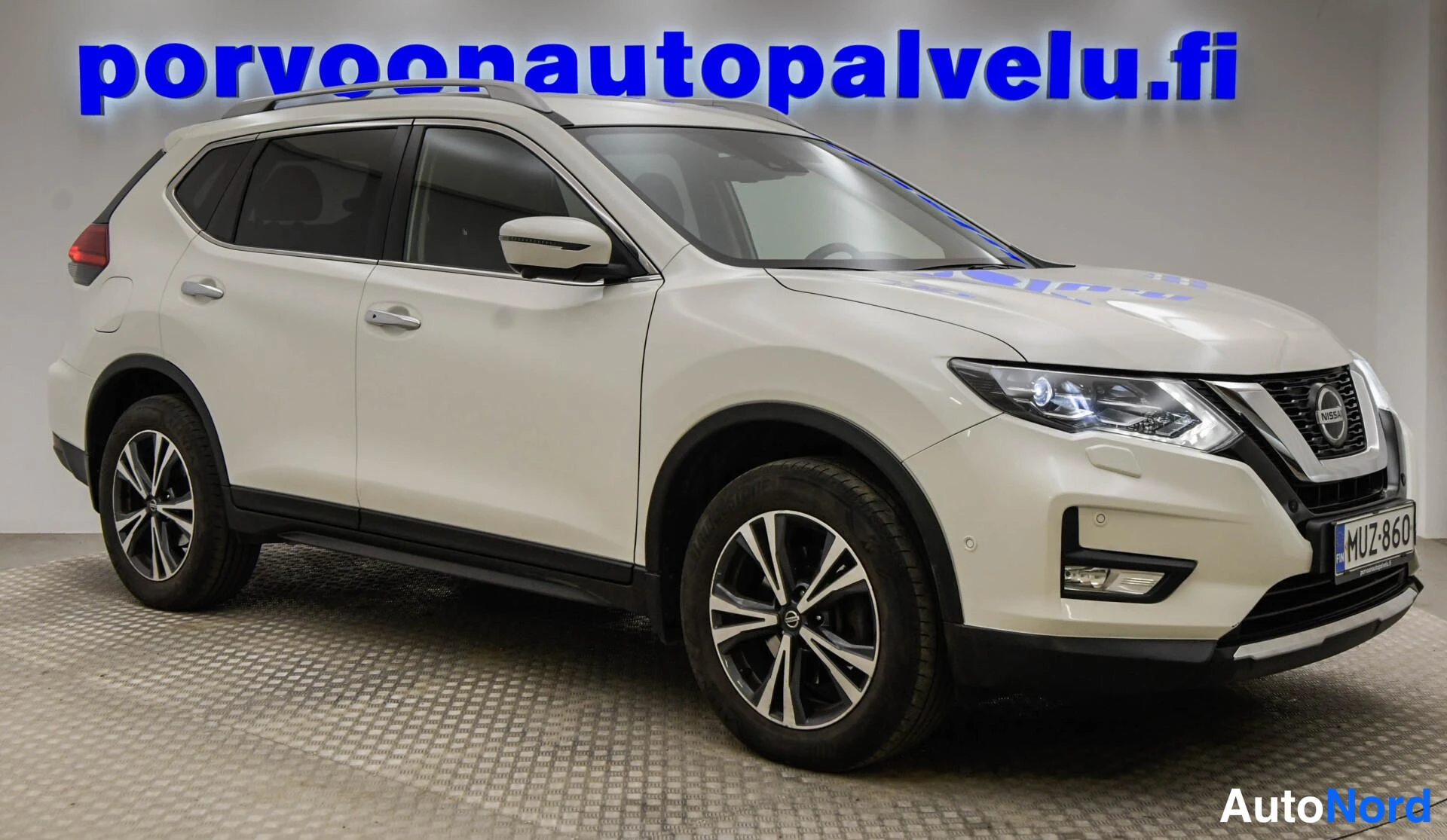 Etuviisto, nokka oikealle: Valkoinen Nissan X-Trail etukulmasta oikealta, rekisterikilpi.