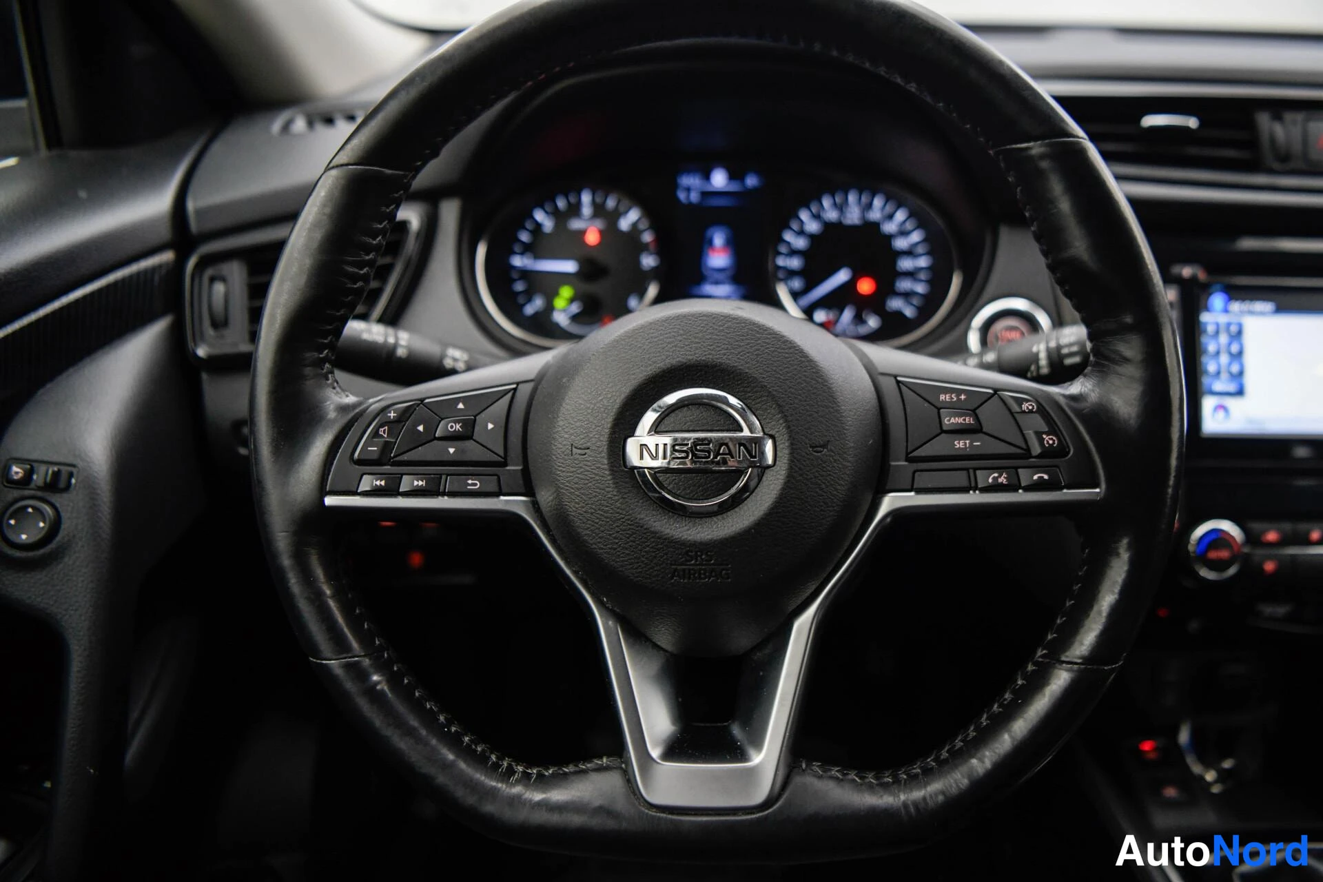 Muu: Ohjauspyörän ja kojelaudan lähikuva, Nissan-merkki ja pyörän näppäimet.