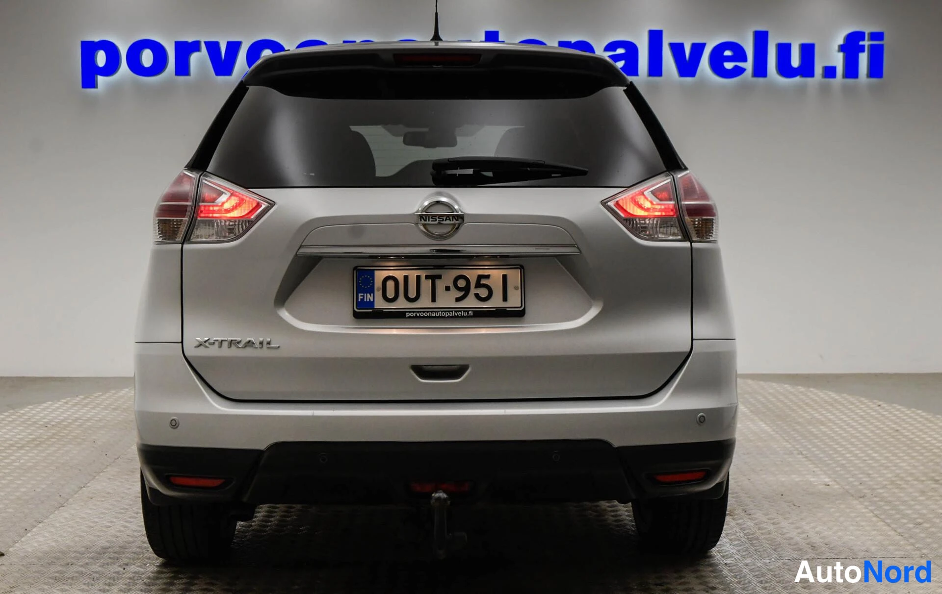 Takaa: Hopeanvärinen Nissan X-Trail suoraan takaa, X-Trail-merkintä ja rekisteritunnus.