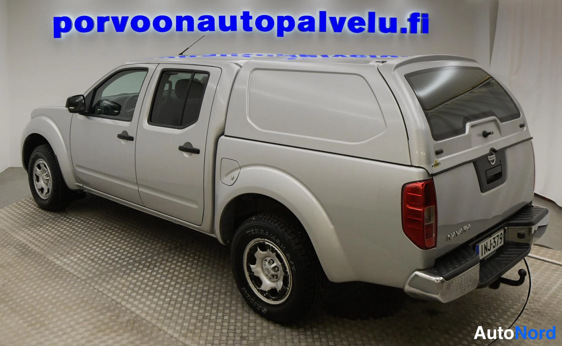 Takaviisto: Hopeanvärinen Nissan Navara takaviistosta, kokolavalle asennettu Vindic-kovakate ja rekisteritunnus näkyvissä.