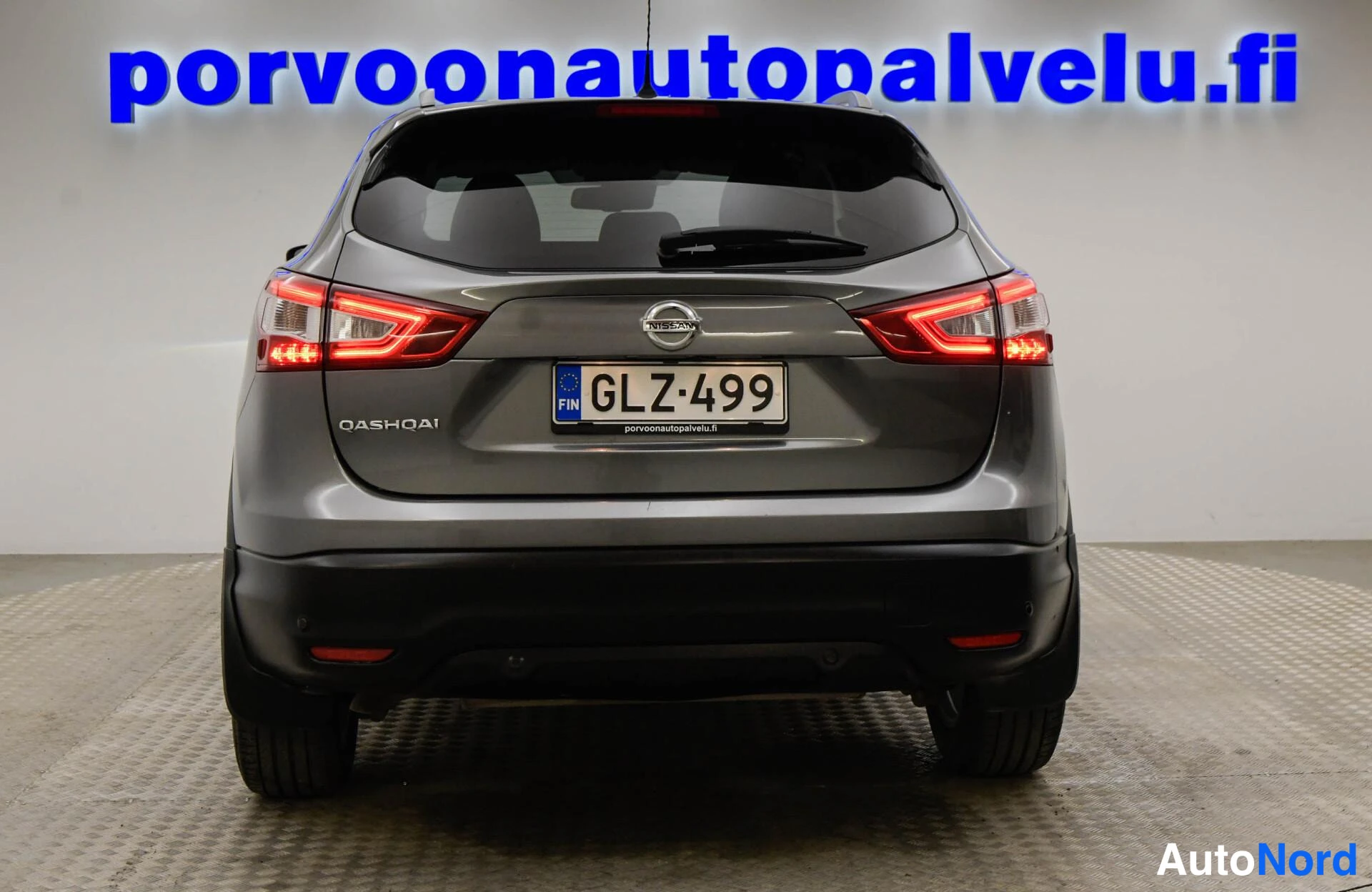 Takaa: Nissan Qashqain takanäkymä, QASHQAI-teksti, Nissan-merkki ja rekisteritunnus, takavalot palavat.