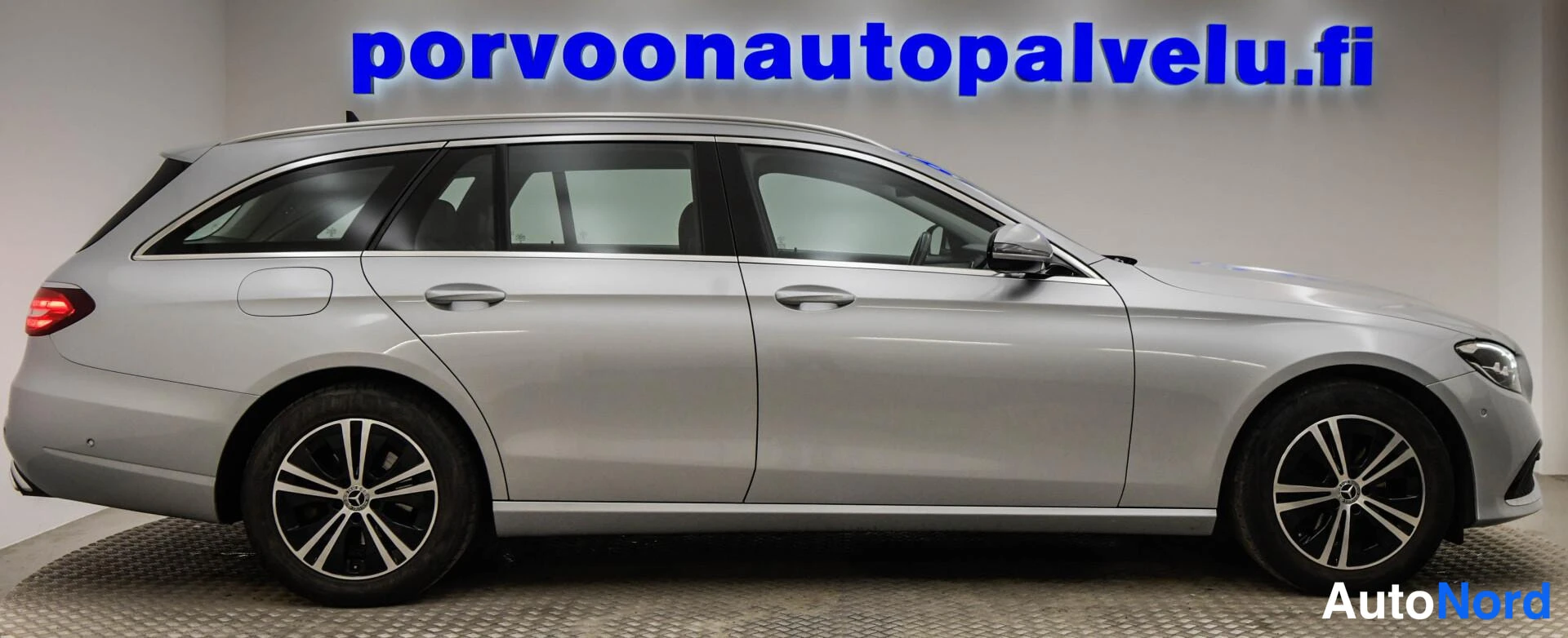 Sivulta: Mercedes-Benz E-sarjan farmarina sivusta kuvattuna, hopeametallinen koripinta, mustat ikkunat ja matalaprofiiliset alumiinivanteet.
