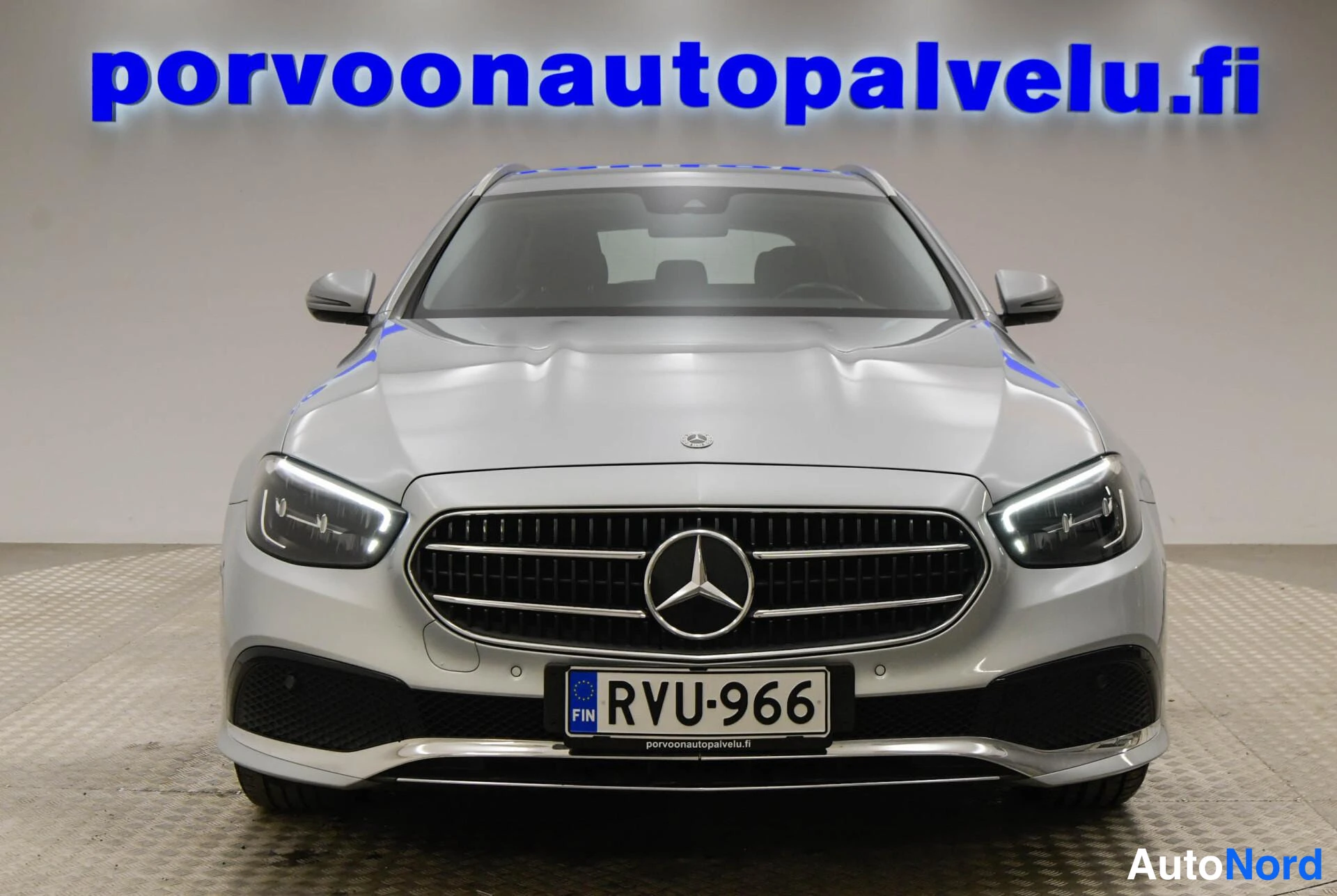 Edestä: Mercedes-Benz E-sarjan farmari suoraan edestä kuvattuna, jyrkänteinen Mercedes-tähti etusäleikössä, suorat LED-ajovalot, rekisterikilpi.
