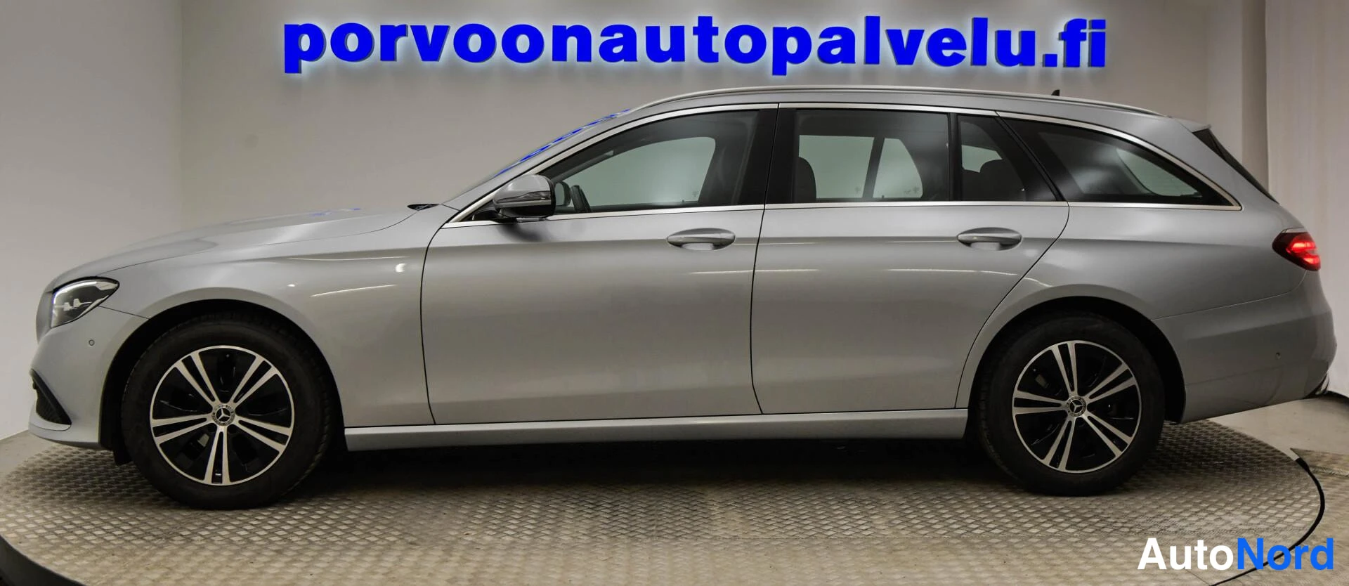 Etuviisto, nokka vasemmalle: Mercedes-Benz E-sarjan farmari etuviistosta vasemmalta, hopeametallinen kori, kaksi ovea näkyvissä ja matalaprofiiliset alumiinivanteet.