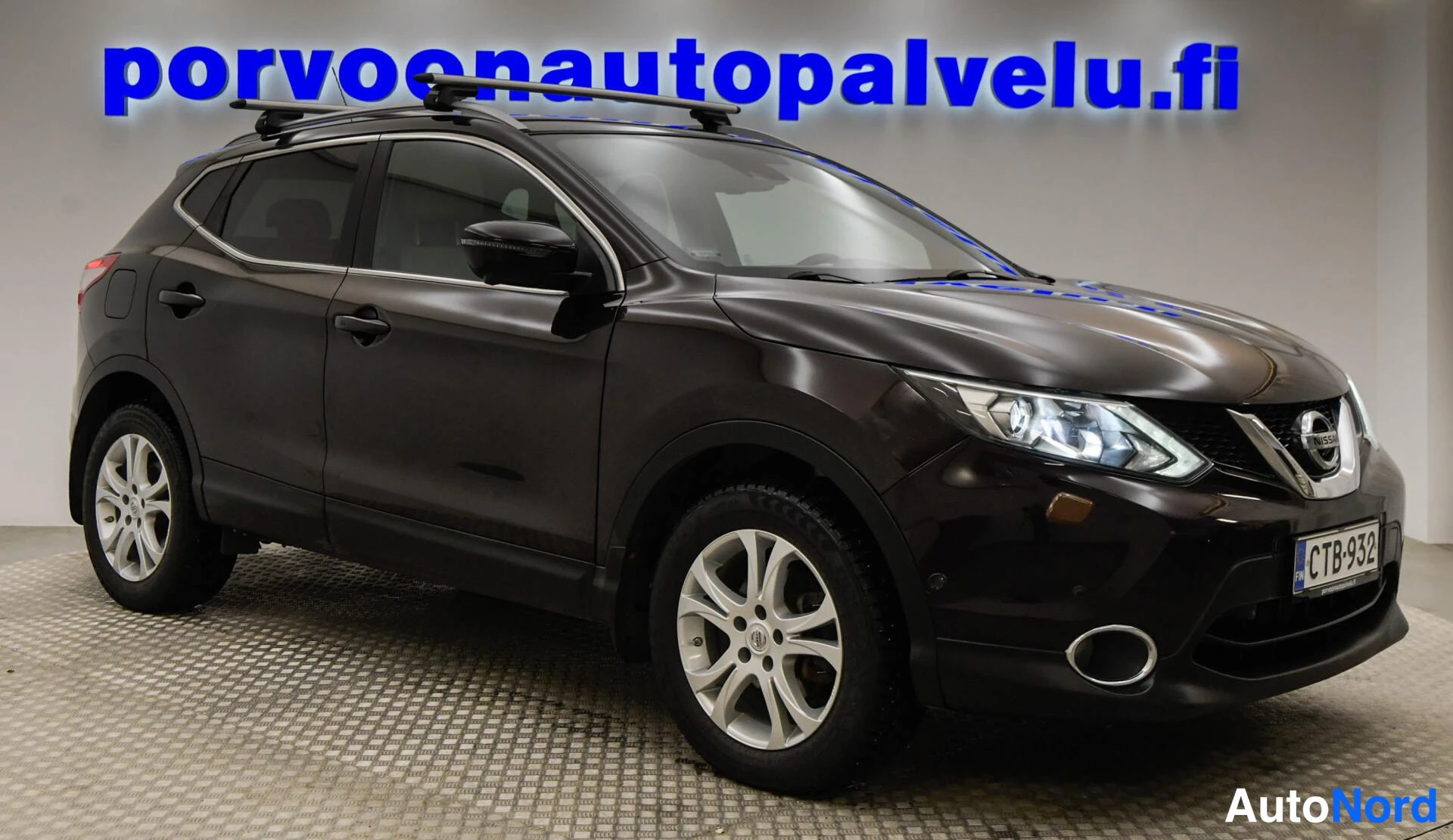 Etuviisto, nokka oikealle: Etukolmasosakulma auton oikealta puolelta; tumma Nissan Qashqai kattotelineillä ja rekisterillä.