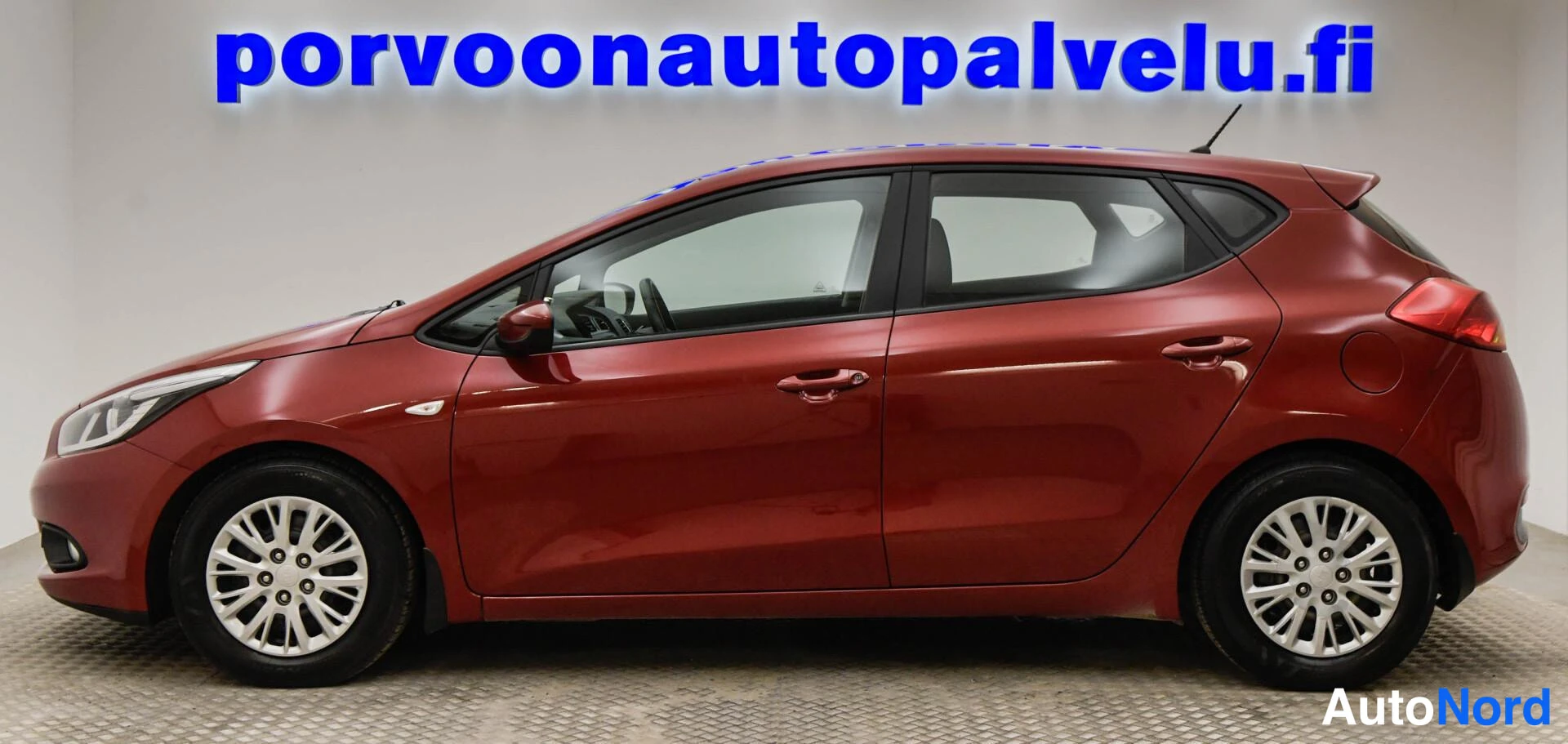 Takaviisto: Kia Ceed -viistotakakuva: tummanpunainen viistoperä, takavalo ja molemmat sivut näkyvät studiotaustaa vasten.