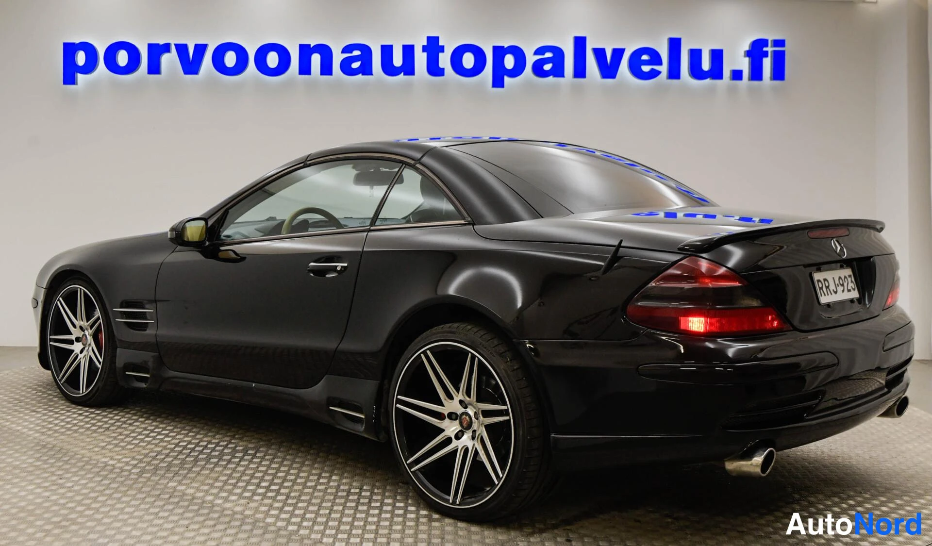 Takaviisto: Musta Mercedes-Benz SL -avolava-auto takakulmasta, suljettu kangaskatto jaHopeavanteet.