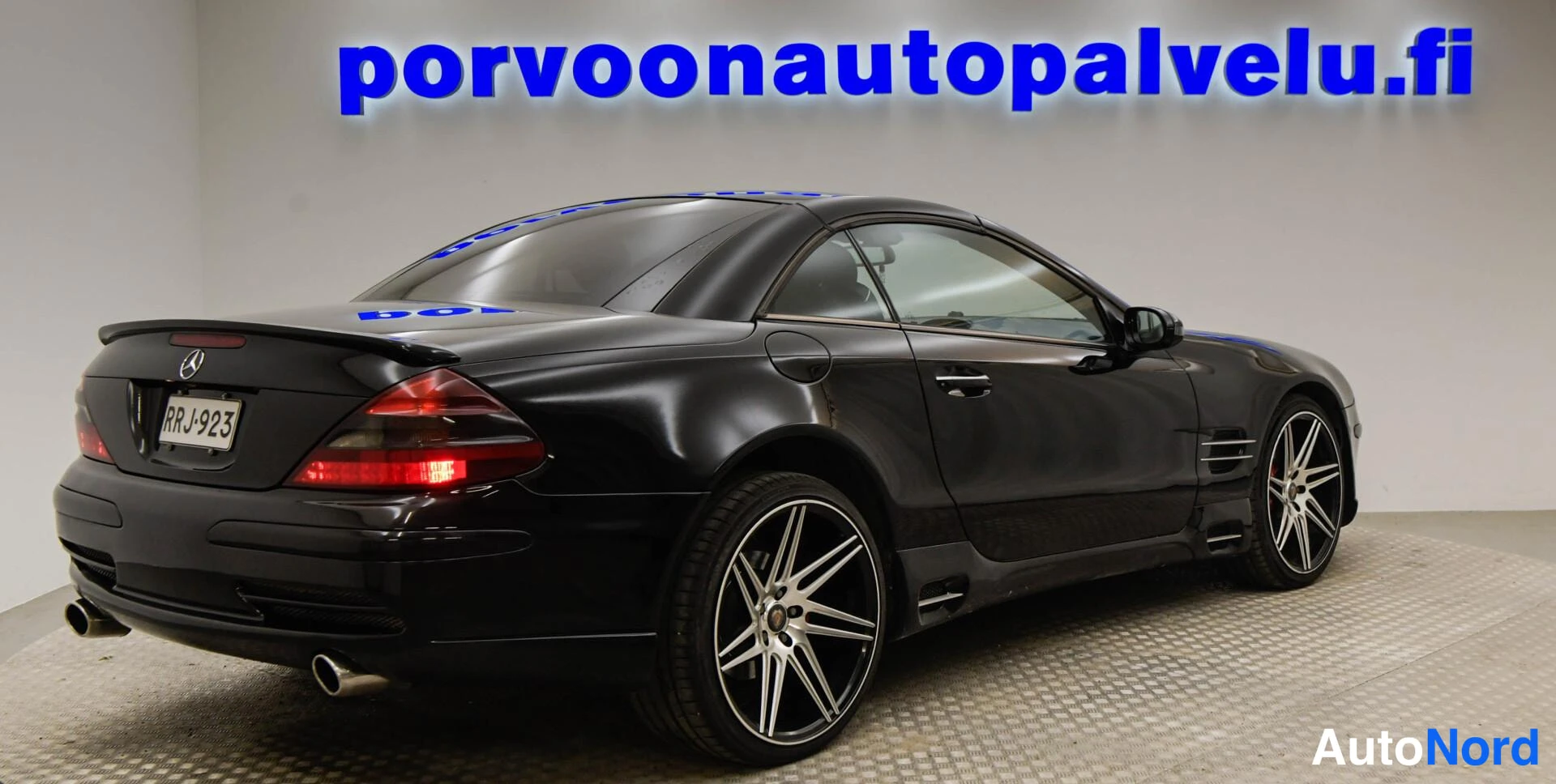 Takaviisto: Musta Mercedes-Benz SL -avolava-auto takakulmasta vasemmalla, rekisteritunnus.