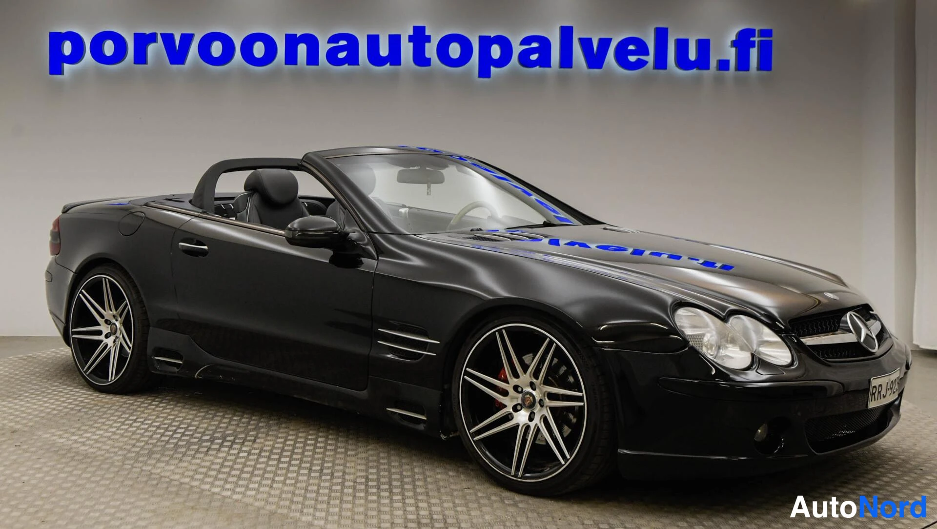 Etuviisto, nokka oikealle: Musta avo-auto etuviistosta oikealta, Mercedes-tähti etusäleikössä, musta katto alas taitettuna.