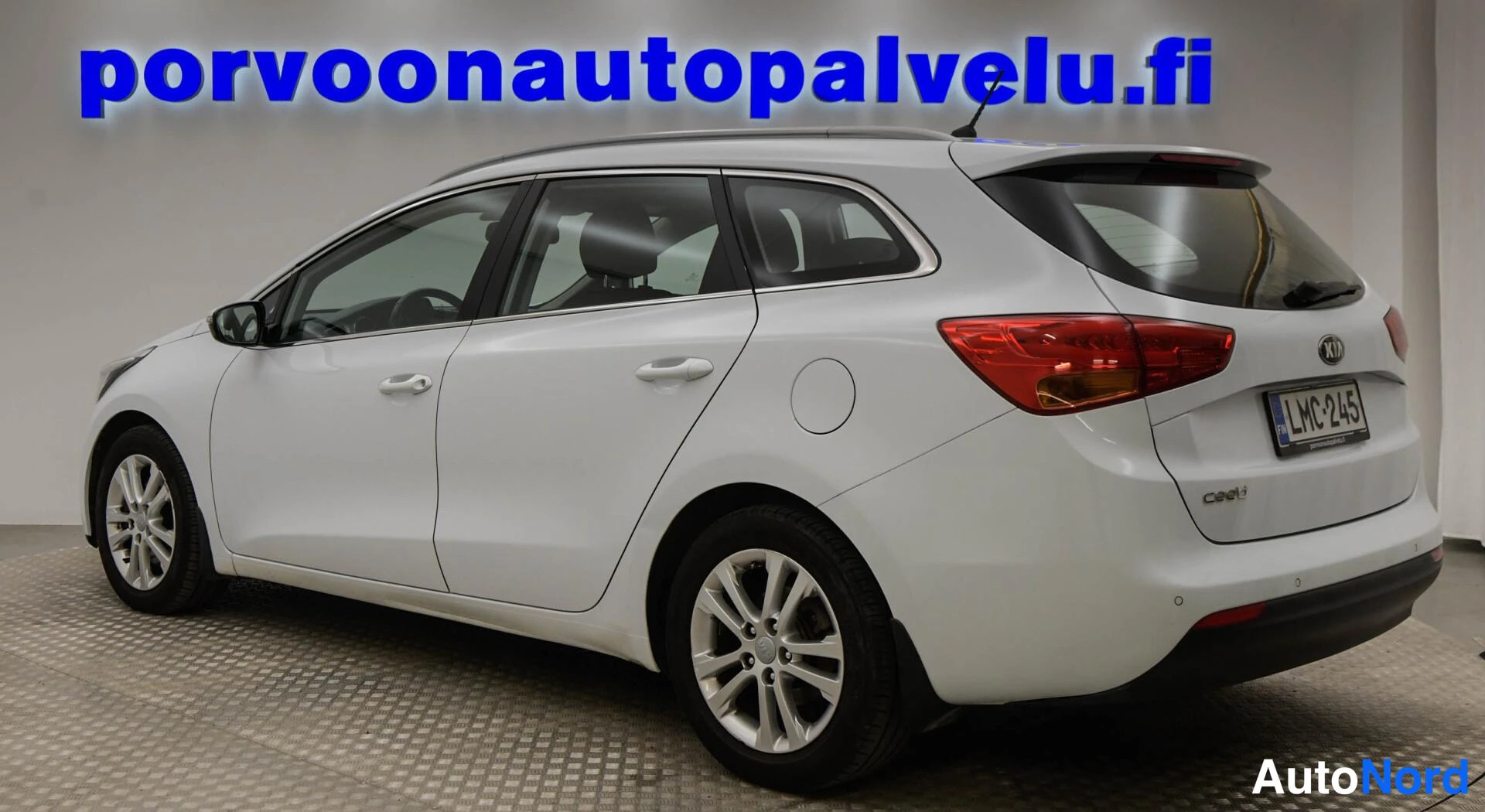 Takaviisto: Kia Ceed -farmari takaa oikealta kuvattuna, punaiset takavalot ja rekisteritunnus näkyvät, korin väri valkoinen.