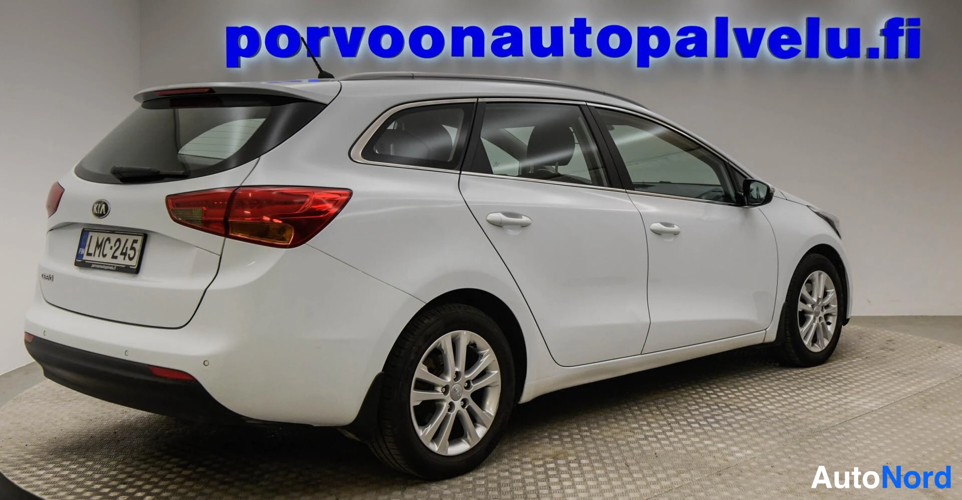 Takaviisto: Kia Ceed -farmari takaa vasemmalta kuvattuna, rekisteritunnus ja punaiset takavalot näkyvät, kori valkoinen.