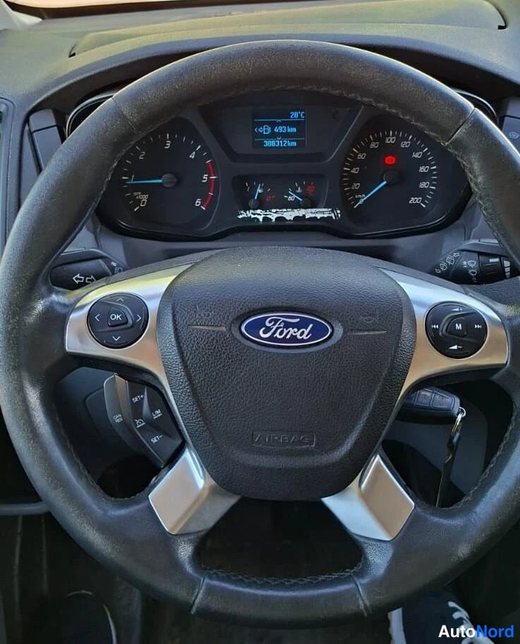 Muu: Ohjauspyörän tarkempi kuva: Ford-merkki, mittaristö taustavalot päällä ja näyttö, jossa lukee '20312 km' ja '20°C'.