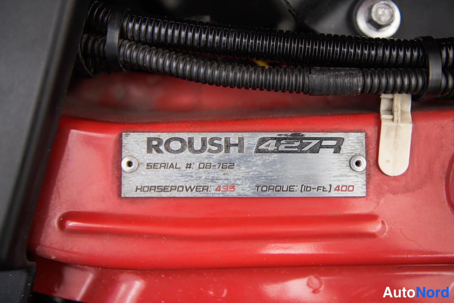 Yksityiskohta: Metallikilpi, jossa lukee 'ROUSH 427R SERIAL #: 08-762 HORSEPOWER: 435 TORQUE: (lb-ft) 400'.