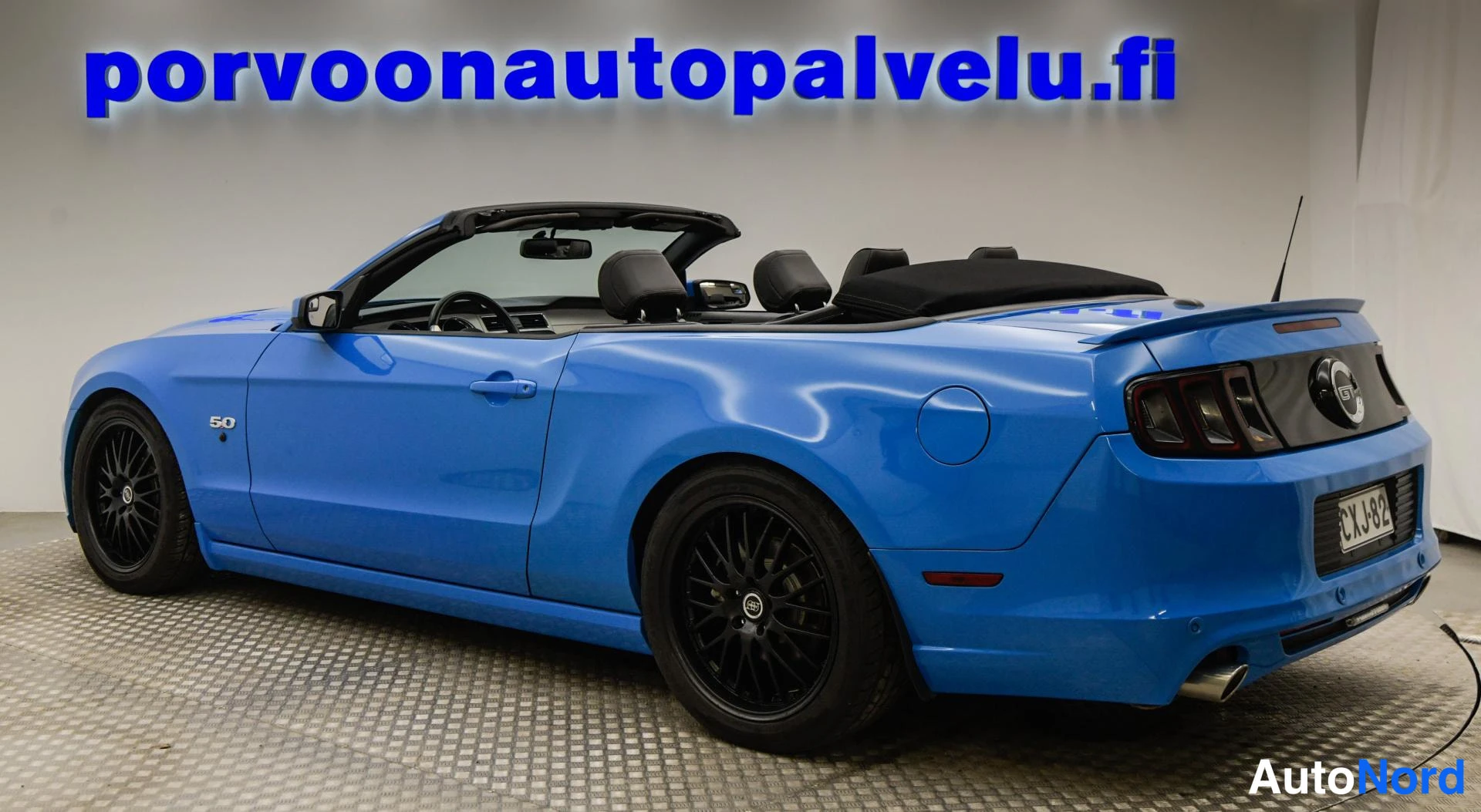 Takaviisto: Sininen Ford Mustang -avonaisauto takakulma, rekisterikilpi, musta katto taitettuna