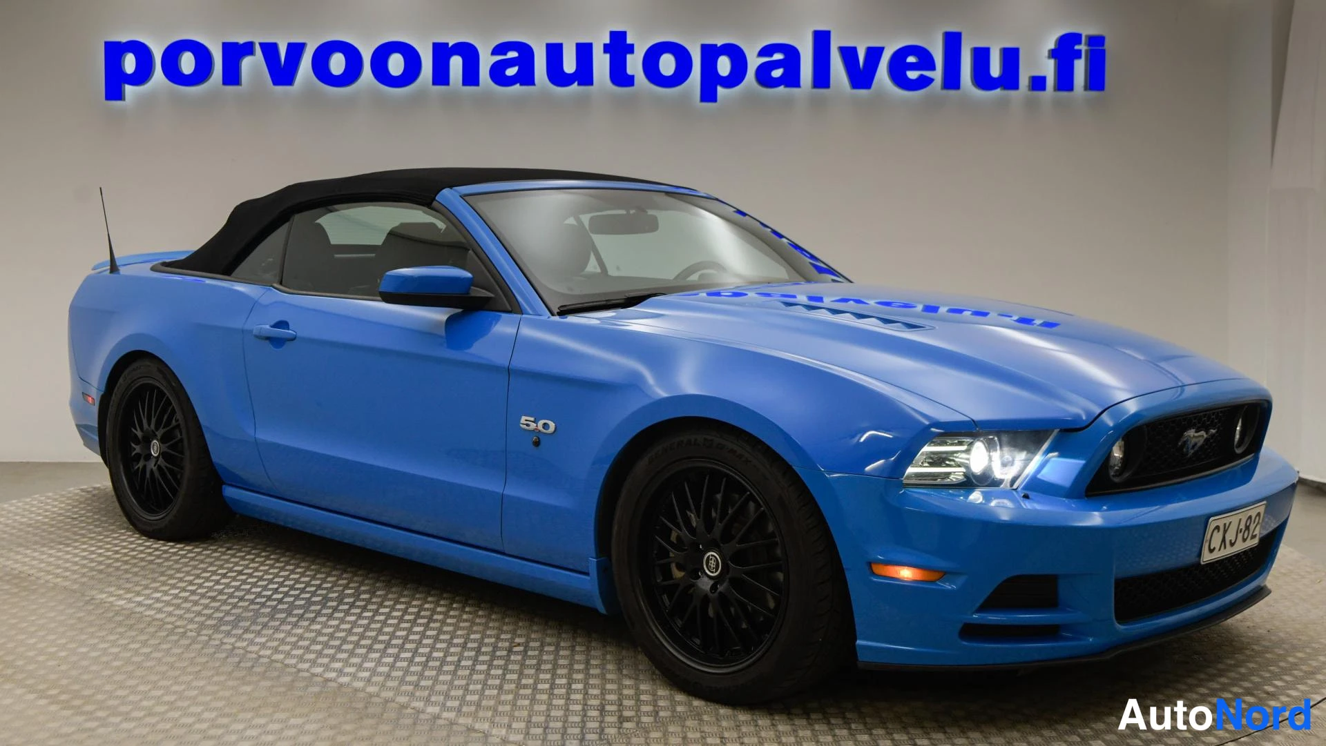 Etuviisto, nokka oikealle: Sininen Ford Mustang GT 5.0 edessä oikealta katsottuna, musta pehmeä katto, rekisterikilpi