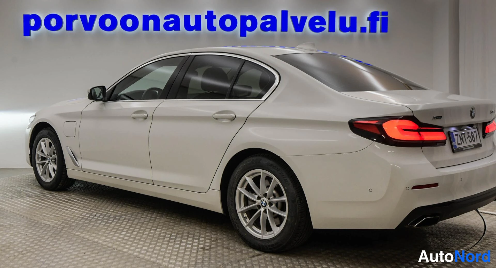 Takaviisto: Valkoisen BMW-sedan takakulma vasemmalta, rekisteritunnus.