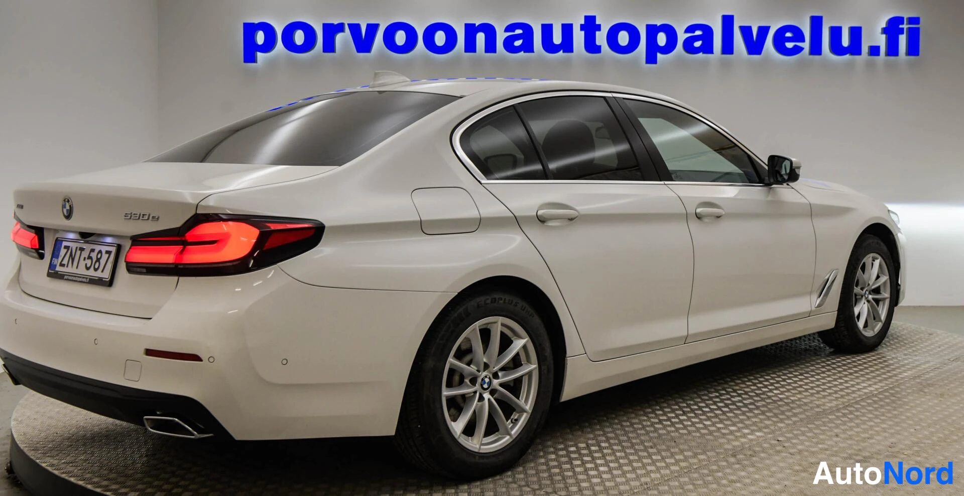 Takaviisto: Valkoisen BMW-sedan takakulma oikealta, rekisteritunnus.