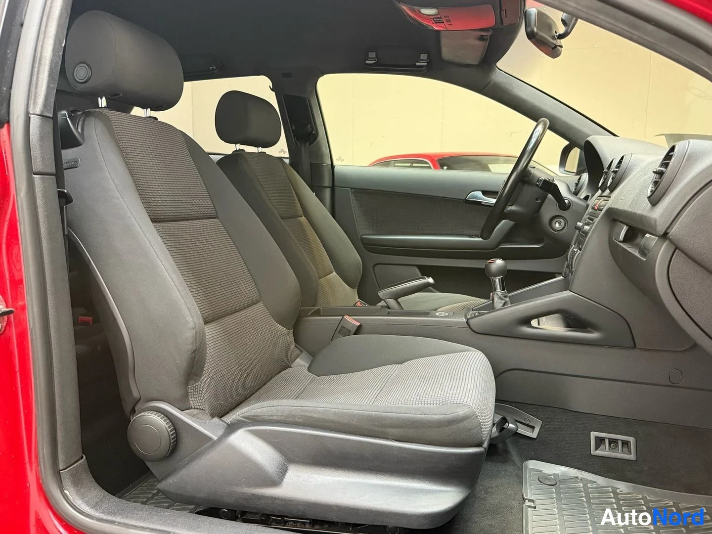Muu: Audi A3:n etupenkki ja takapenkki sivulta: kankaiset istuimet, tumma sisusta, vaihtokeppi ja ohjauspyörä.