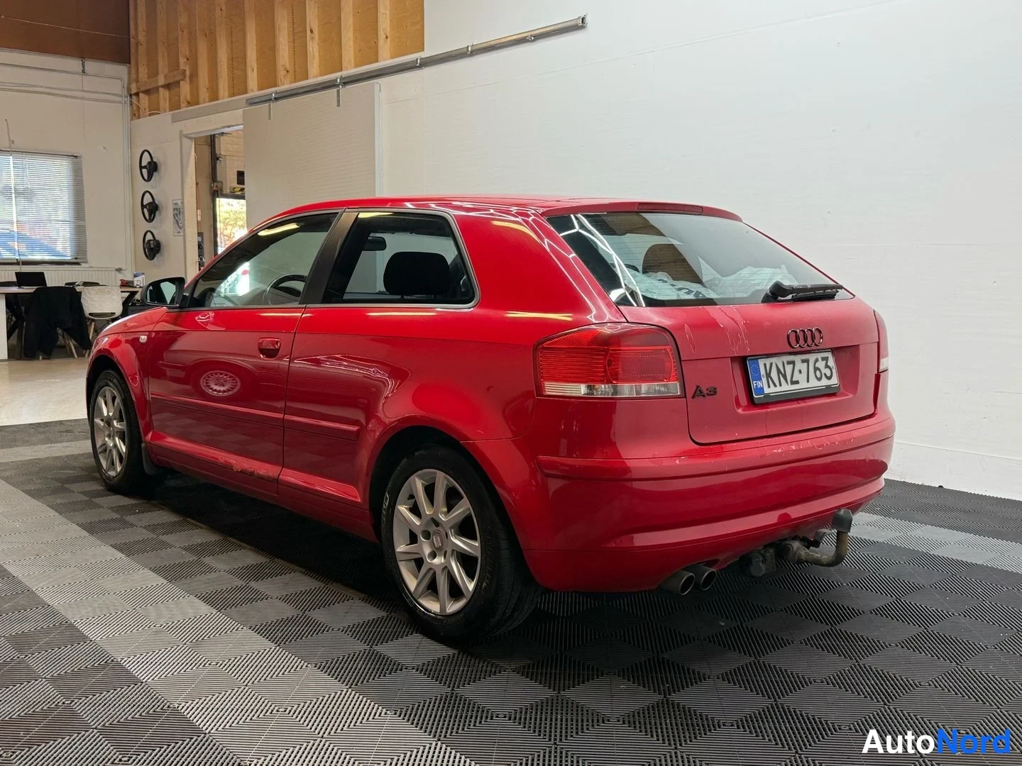 Takaviisto: Punaisen Audi A3:n takakulma, takavalojen ja A3-tunnuksen kohdalla kuvattuna, rekisteritunnus.