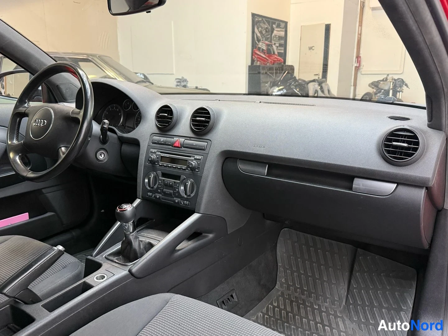 Muu: Kojetaulu ja keskikonsoli Audi A3:sta: radiopaneeli, ilmastointiaukot, manuaalivaihtehan ja kumimatot.