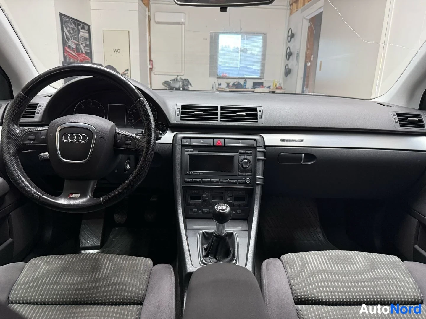 Muu: Kojelauta ja ohjaamo suoraan edestä: Audi-merkillinen ohjauspyörä, manuaalivaihtaja ja Audi-navigation radio.